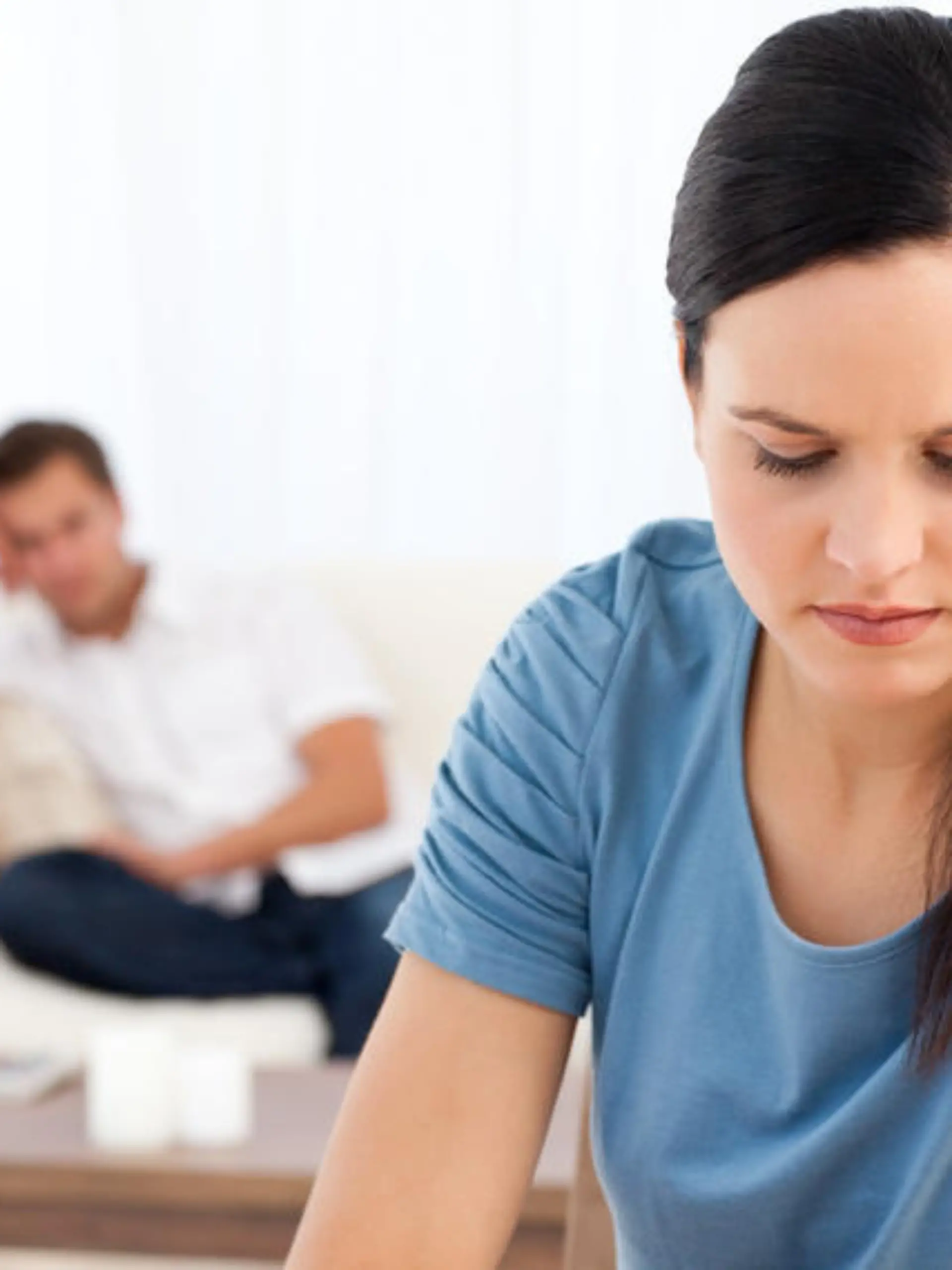 Woman thinking at a table while her boyfriend waiting in the background