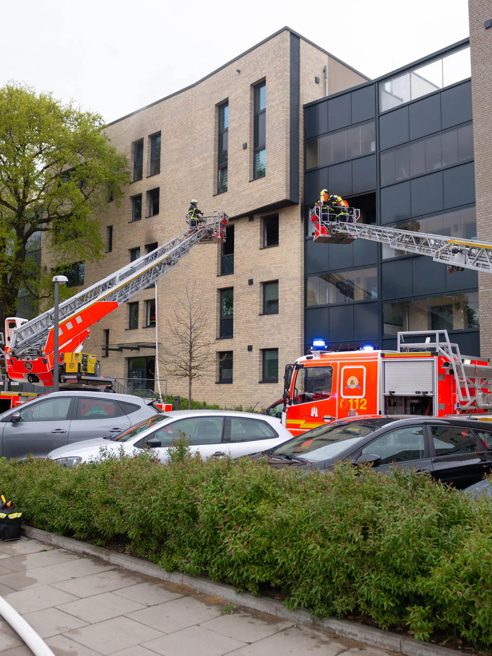 ARCHIV - 01.05.2020, Hamburg: Zwei Drehleitern und mehrere Einsatzfahrzeuge stehen vor einem Wohnhaus. Weil er seine Ex-Frau mit einem Messer angegriffen und sie sowie einen Sohn mit Benzin übergossen und angezündet haben soll, muss sich ein 50-Jähriger vor dem Hamburger Landgericht verantworten. Die Strafkammer will am 04. Mai 2021 ihr Urteil verkünden. (zu dpa «Urteil erwartet in Prozess um Mordversuch - Frau und Sohn angezündet») Foto: Jonas Walzberg/dpa +++ dpa-Bildfunk +++