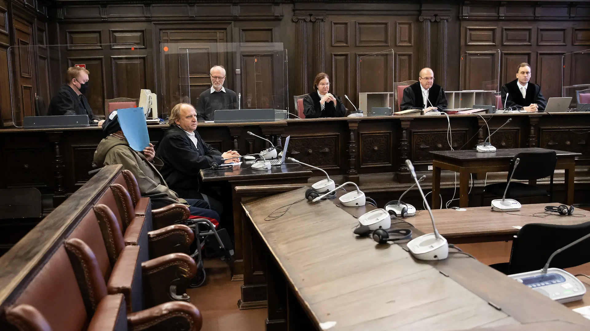 ARCHIV - 13.11.2020, Hamburg: Matthias Steinmann (2.v.r), Vorsitzender Richter am Landgericht, der Angeklagte (2.v.l), sein Anwalt Tim Burkert (3.v.l) und weitere Prozessbeteiligte sitzen zu Beginn des Prozesses im Gerichtssaal im Strafjustizgebäude. Weil er seine Ex-Frau mit einem Messer angegriffen und sie sowie einen Sohn mit Benzin übergossen und angezündet haben soll, muss sich ein 50-Jähriger vor dem Hamburger Landgericht verantworten. Die Strafkammer will am 04. Mai 2021 ihr Urteil verkünden. (zu dpa «Urteil erwartet in Prozess um Mordversuch - Frau und Sohn angezündet») Foto: Christian Charisius/dpa/Pool/dpa +++ dpa-Bildfunk +++