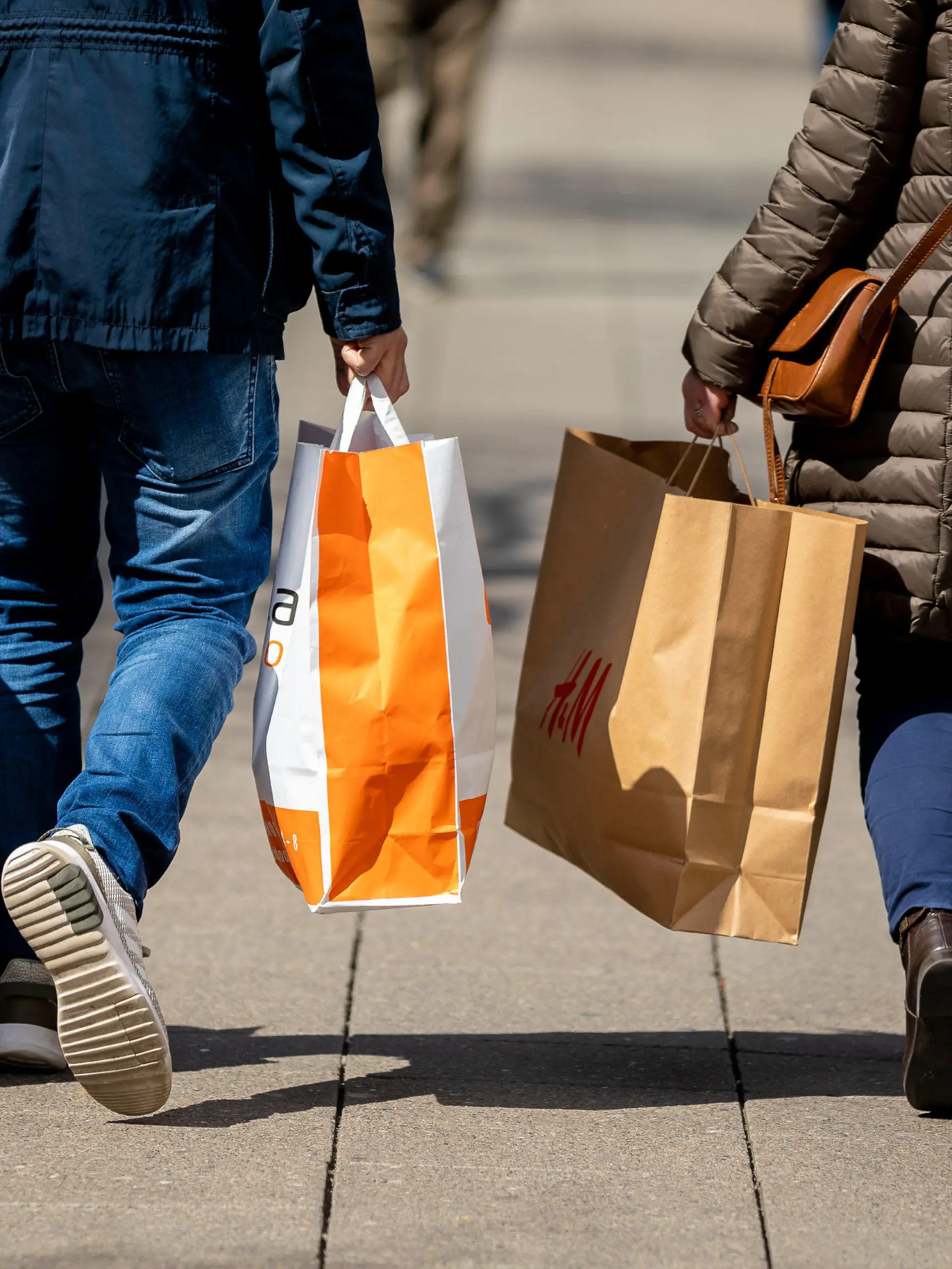 26.04.2021, Niedersachsen, Hannover: Passanten gehen mit Papiertüten in den Händen durch die Innenstadt. Foto: Moritz Frankenberg/dpa +++ dpa-Bildfunk +++