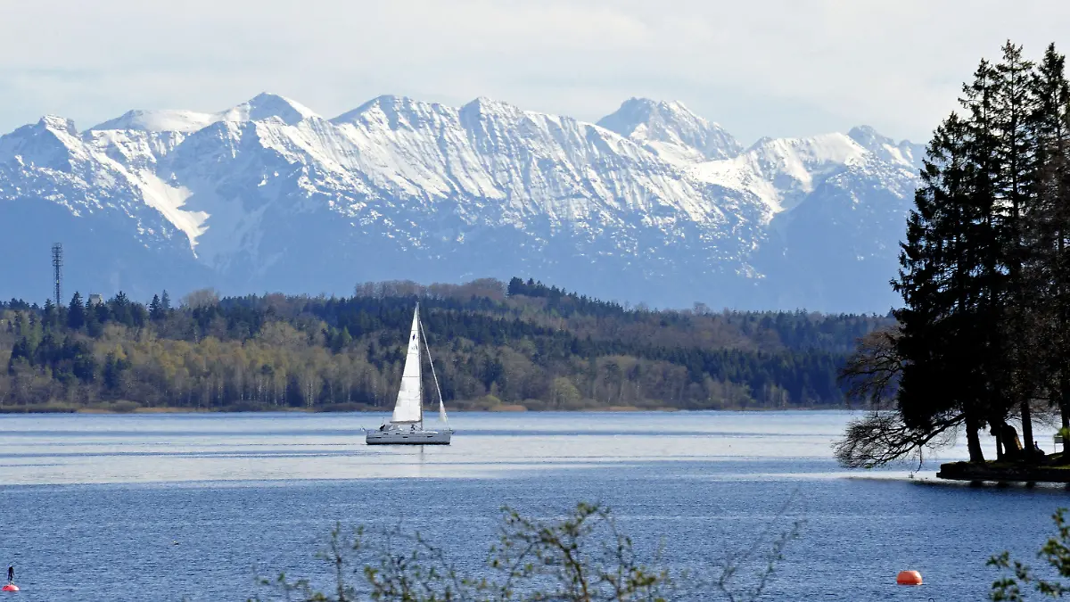 Eines der ersten Segelboote gleitet am Donnerstag (26.04.2012) vor der Kulisse der verschneiten Alpen bei Tutzing (Oberbayern) über den Starnberger See. Laut Wetterbericht herrscht in den nächsten Tagen in Bayern weiterhin hochsommerliches Wetter. Foto: Ursula Düren dpa/lby +++(c) dpa - Bildfunk+++