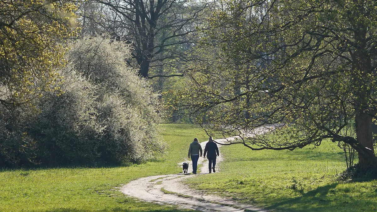 03.05.2021, Hamburg: Passanten gehen mit einem Hund im Jenischpark spazieren. Foto: Marcus Brandt/dpa +++ dpa-Bildfunk +++