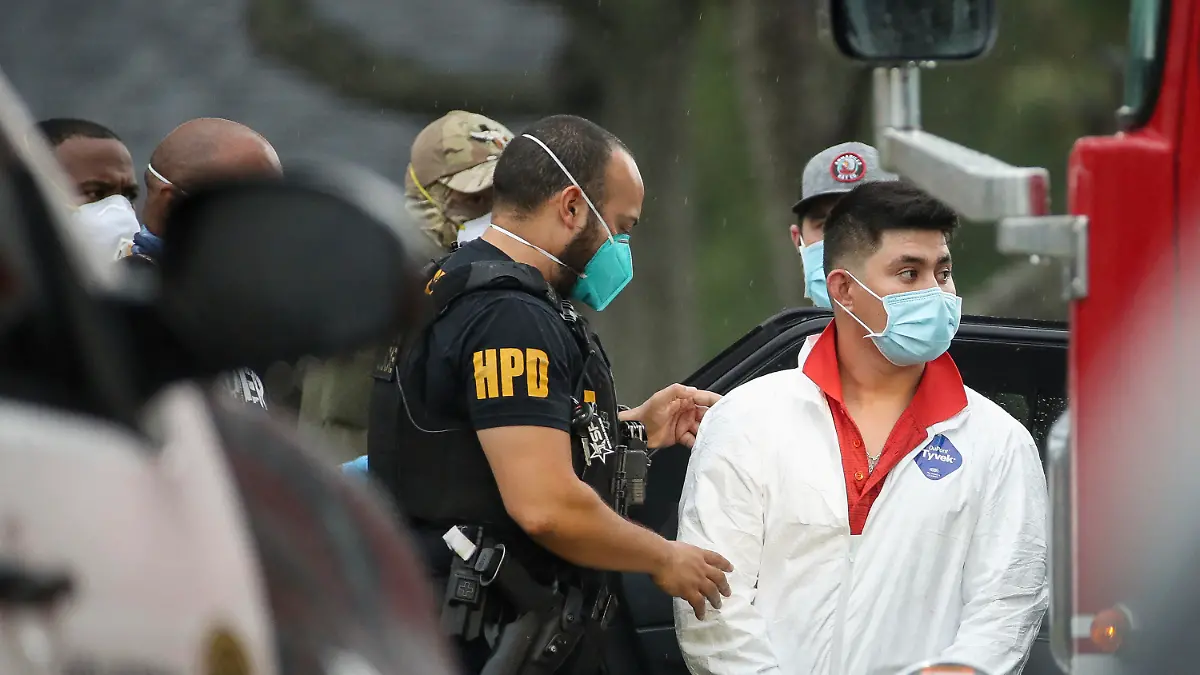 A Houston Police officer takes into a custody a man who was found inside the house where more than 90 undocumented migrants were found on the 12200 block of Chessington Drive on Friday, April 30, 2021, in Houston. A Houston Police officials said the case will be handled by federal authorities. (Godofredo A. Vásquez/Houston Chronicle via AP)