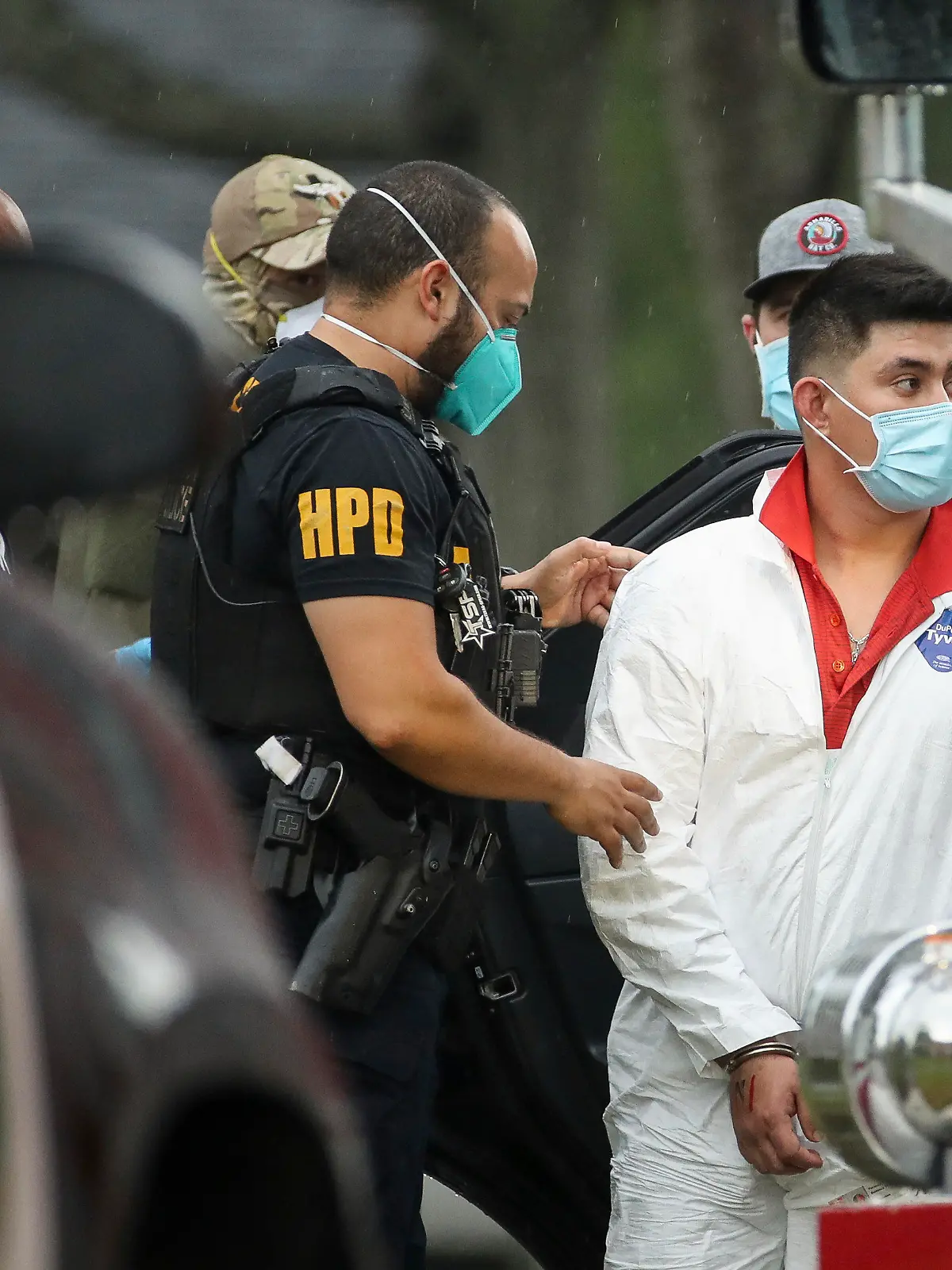 A Houston Police officer takes into a custody a man who was found inside the house where more than 90 undocumented migrants were found on the 12200 block of Chessington Drive on Friday, April 30, 2021, in Houston. A Houston Police officials said the case will be handled by federal authorities. (Godofredo A. Vásquez/Houston Chronicle via AP)