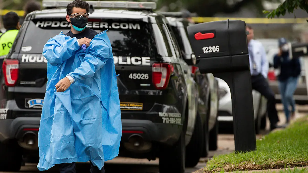 A Houston Fire Department paramedic takes off a layer of PPE after exiting the scene of a human smuggling case, where more than 90 undocumented migrants were found inside a home on the 12200 block of Chessington Drive on Friday, April 30, 2021, in Houston. A Houston Police officials said the case will be handled by federal authorities. (Godofredo A. Vásquez/Houston Chronicle via AP)
