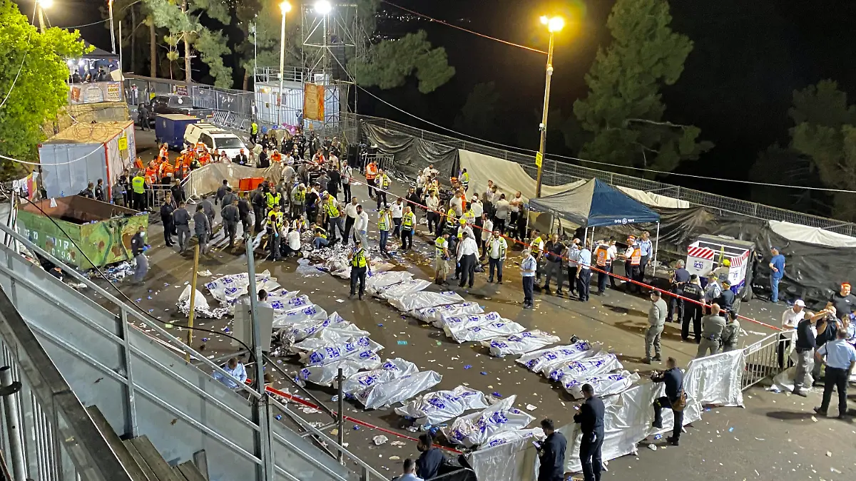 30.04.2021, Israel, Meron: Israelische Sicherheitsbeamte und Rettungskräfte stehen neben den Leichen der Opfer, die während Feierlichkeiten zum jüdischen Feiertag Lag BaOmer auf dem Berg Meron gestorben sind. Bei einer Massenpanik auf einem jüdischen Fest im Norden Israels sind nach Angaben von Rettungskräften mindestens 38 Menschen ums Leben gekommen. Foto: Ishay Jerusalemite/Behadrei Haredim/AP/dpa +++ dpa-Bildfunk +++