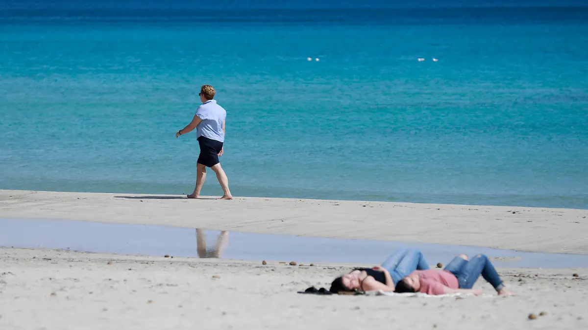 10.03.2023, Spanien, Son Servera: Eine Frau spaziert am Strand von Cala Millor auf Mallorca. Ungewöhnlich hohe Temperaturen für diese Jahreszeit werden für dieses Wochenende auf Mallorca erwartet. Foto: Clara Margais/dpa +++ dpa-Bildfunk +++