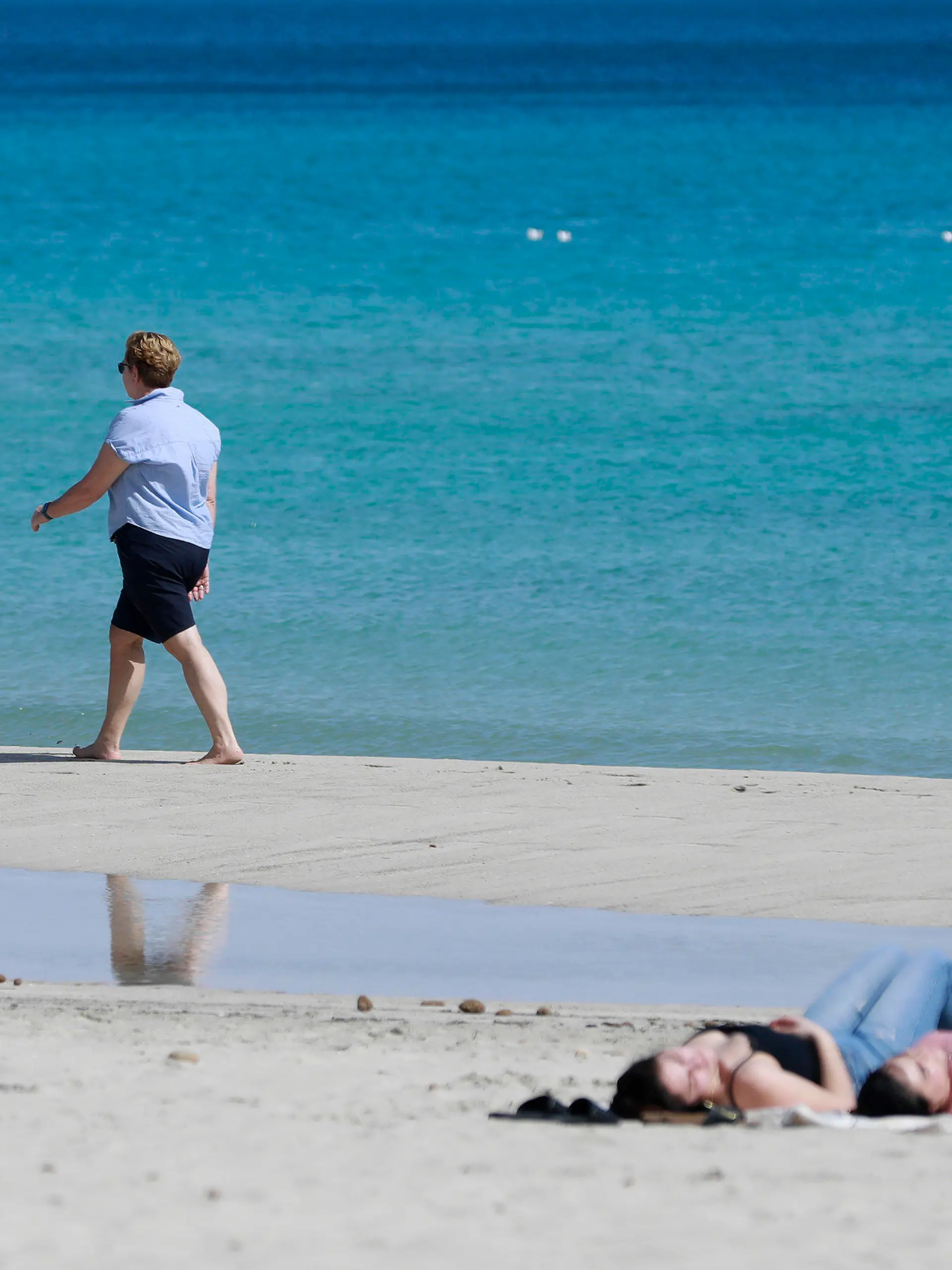 10.03.2023, Spanien, Son Servera: Eine Frau spaziert am Strand von Cala Millor auf Mallorca. Ungewöhnlich hohe Temperaturen für diese Jahreszeit werden für dieses Wochenende auf Mallorca erwartet. Foto: Clara Margais/dpa +++ dpa-Bildfunk +++