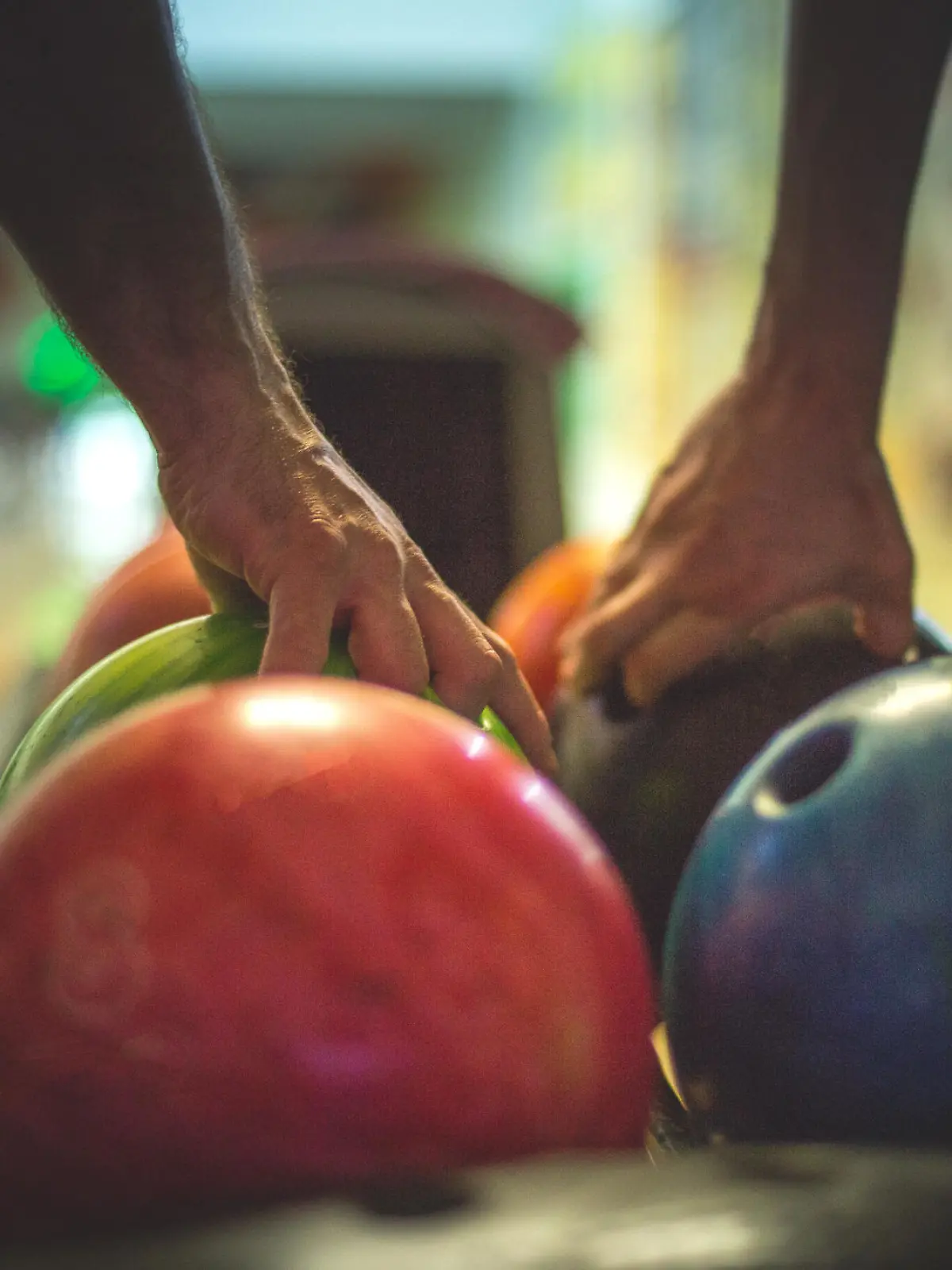 Hände greifen zur Bowlingkugel an der Bowlingbahn
