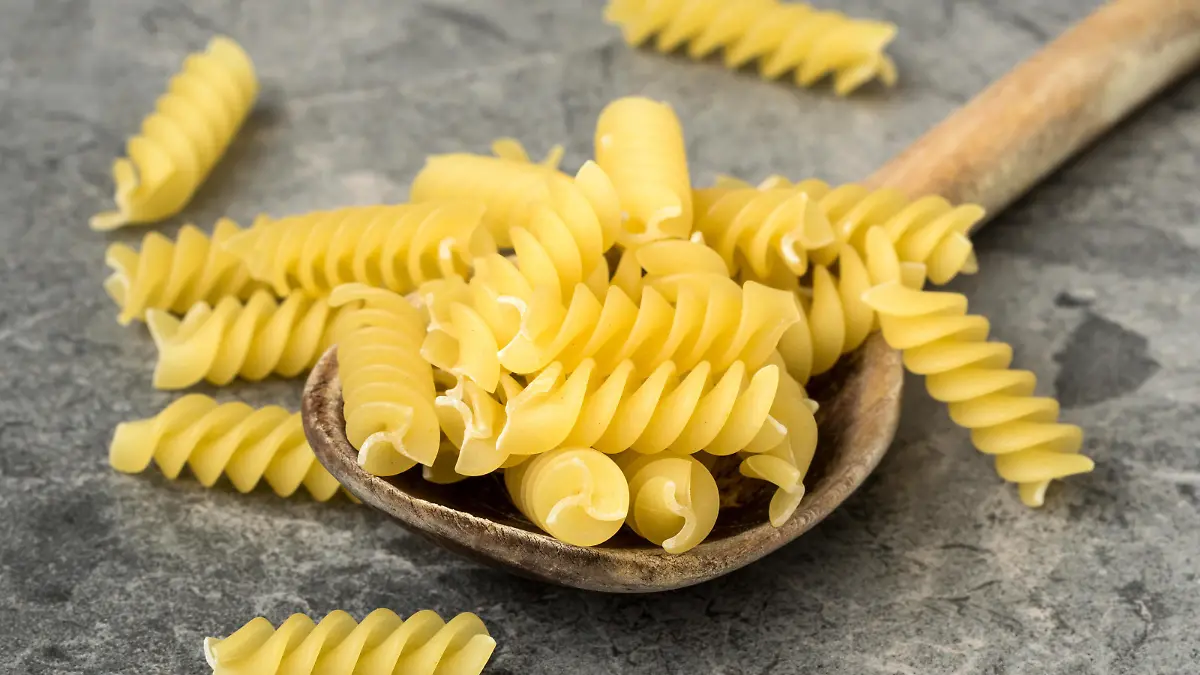 Uncooked pasta in wooden spoon closeup