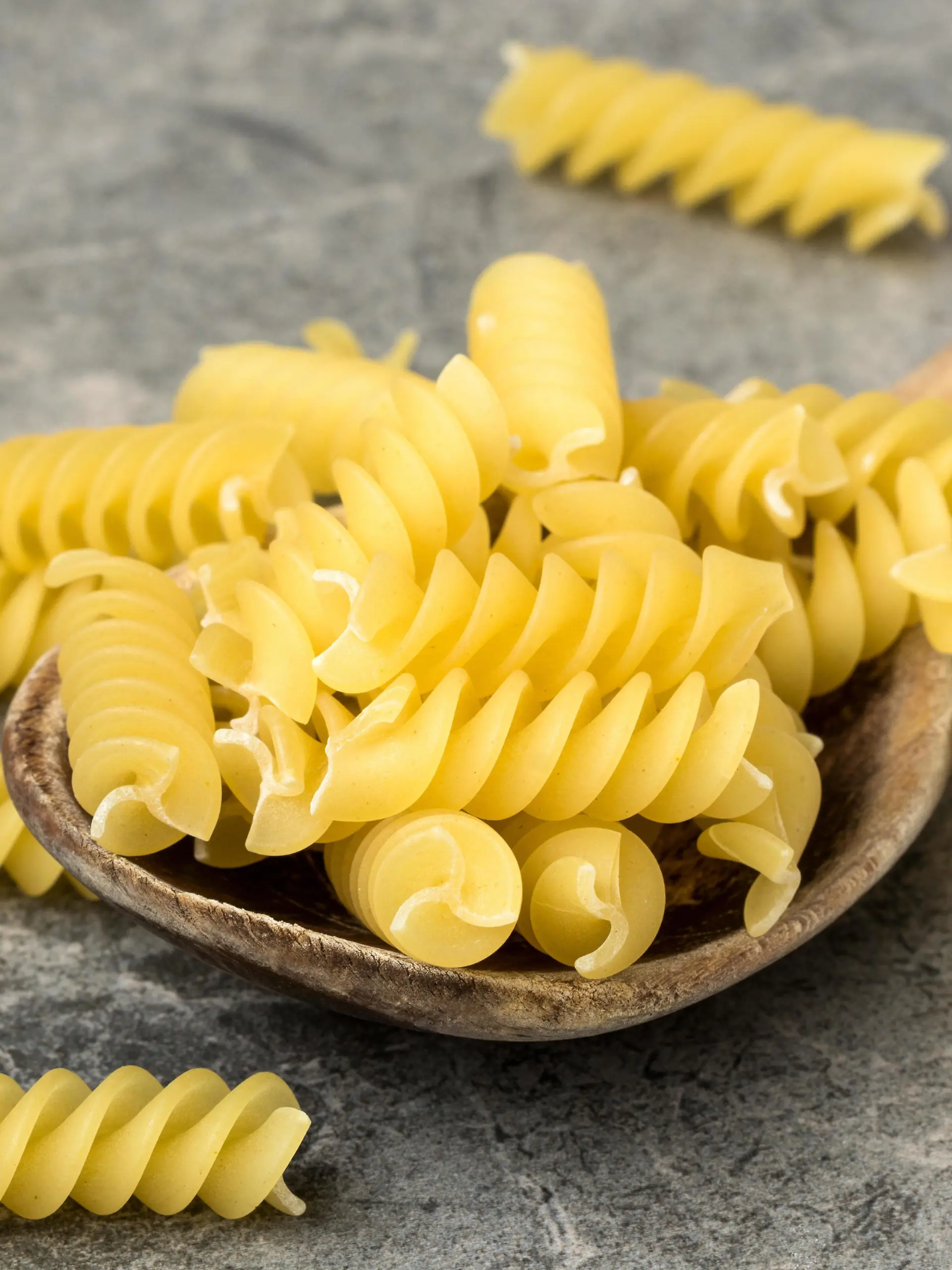 Uncooked pasta in wooden spoon closeup