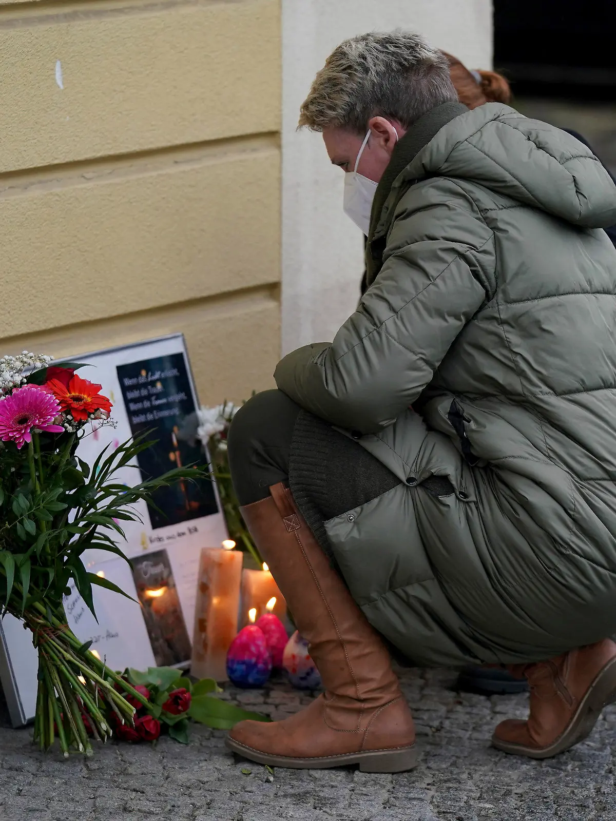 Two women drop flowers in front of the 'Thusnelda von Saldern Haus' at the Oberlinklinik (Oberlin Clinic) in Potsdam near Berlin, Germany, Thursday, April 29, 2021. German police say a woman has been detained after four people were found dead at a hospital in the eastern city of Potsdam. (AP Photo/Michael Sohn)