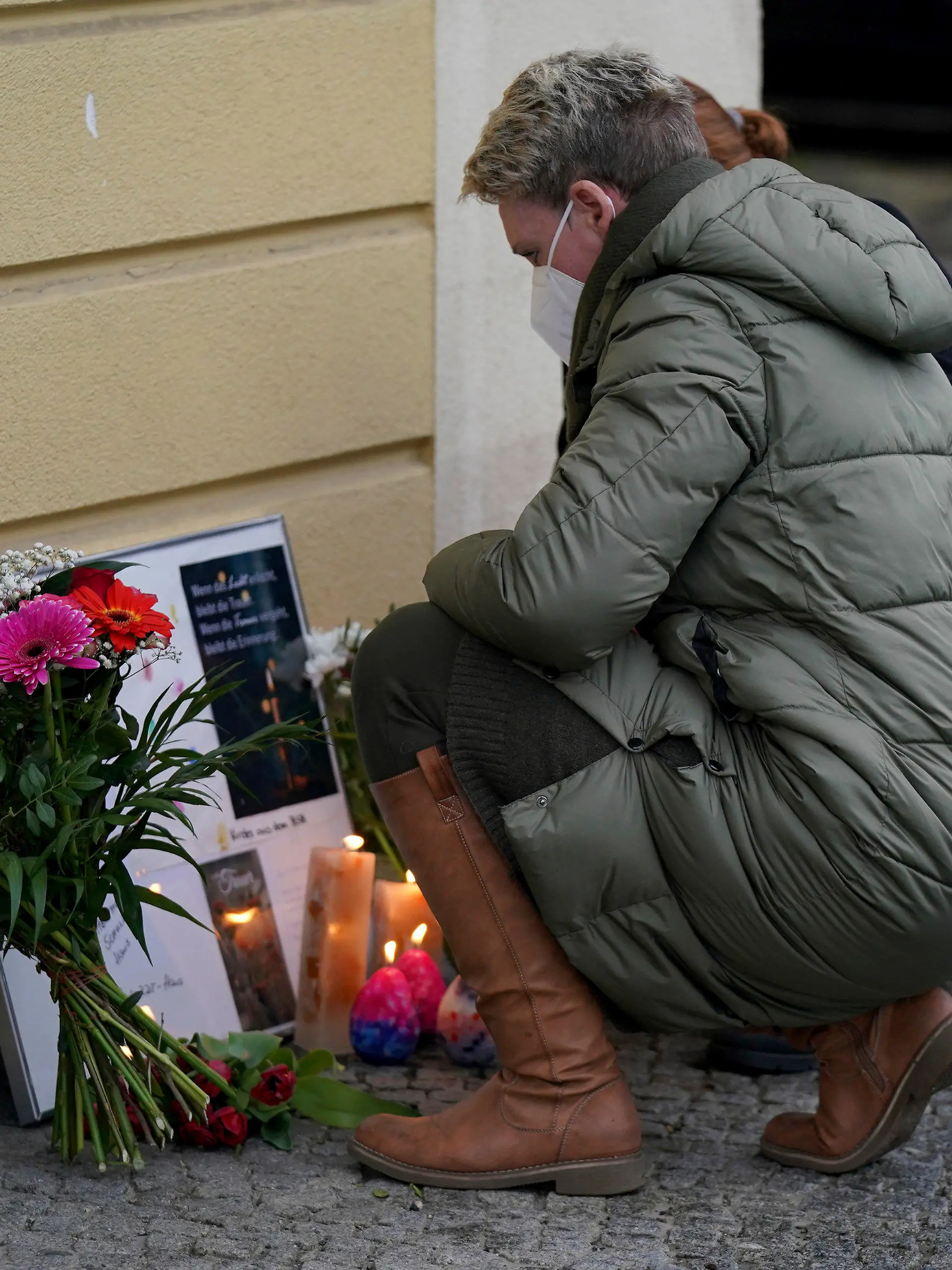 Two women drop flowers in front of the 'Thusnelda von Saldern Haus' at the Oberlinklinik (Oberlin Clinic) in Potsdam near Berlin, Germany, Thursday, April 29, 2021. German police say a woman has been detained after four people were found dead at a hospital in the eastern city of Potsdam. (AP Photo/Michael Sohn)