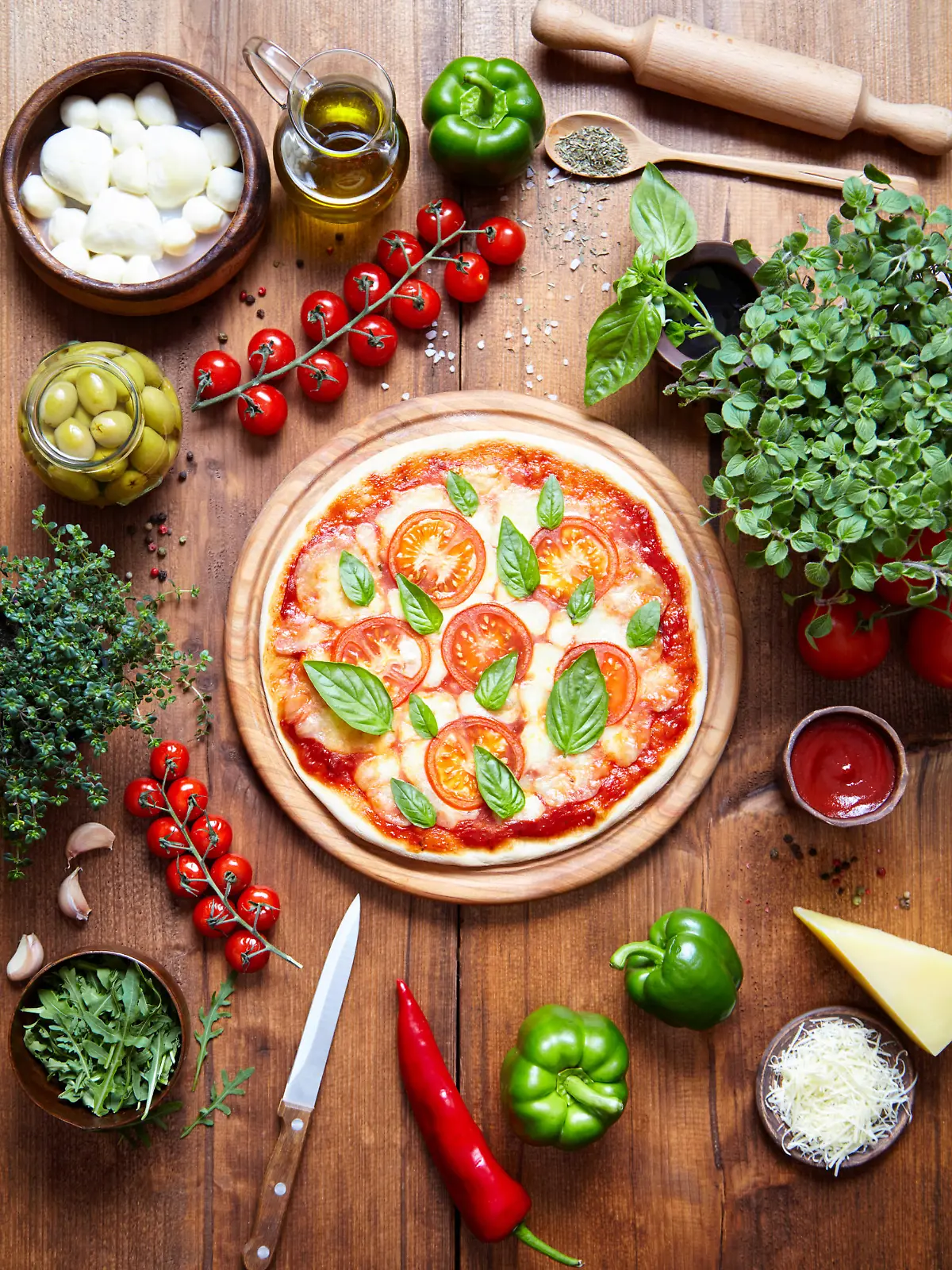 Pizza margarita on a wooden plate and the ingredient from which it is made. Italian food background. View from above. Mozzarella, sauce, pepper, oregano, parmesan, olive oil, in frame. Flat lay