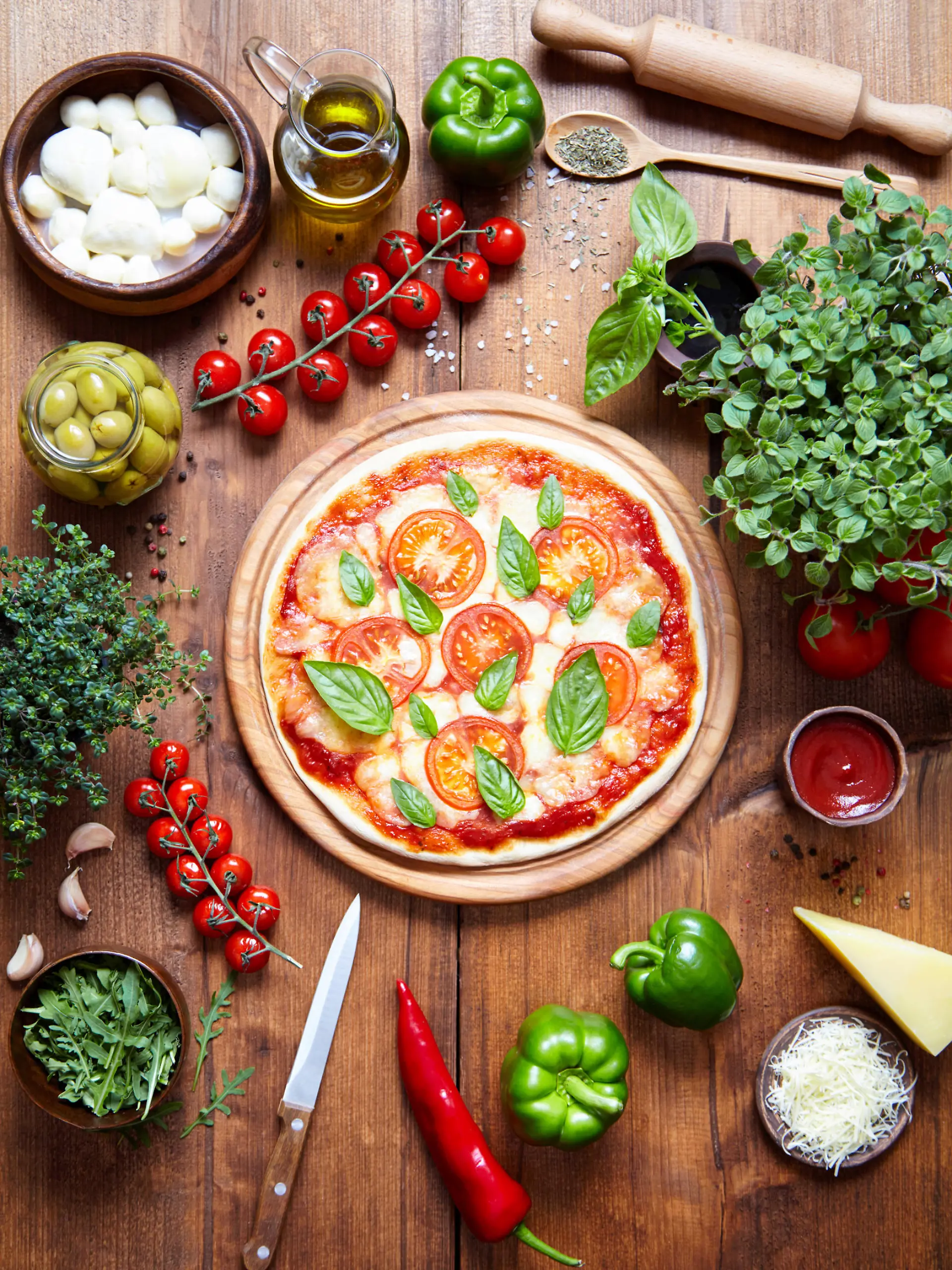Pizza margarita on a wooden plate and the ingredient from which it is made. Italian food background. View from above. Mozzarella, sauce, pepper, oregano, parmesan, olive oil, in frame. Flat lay