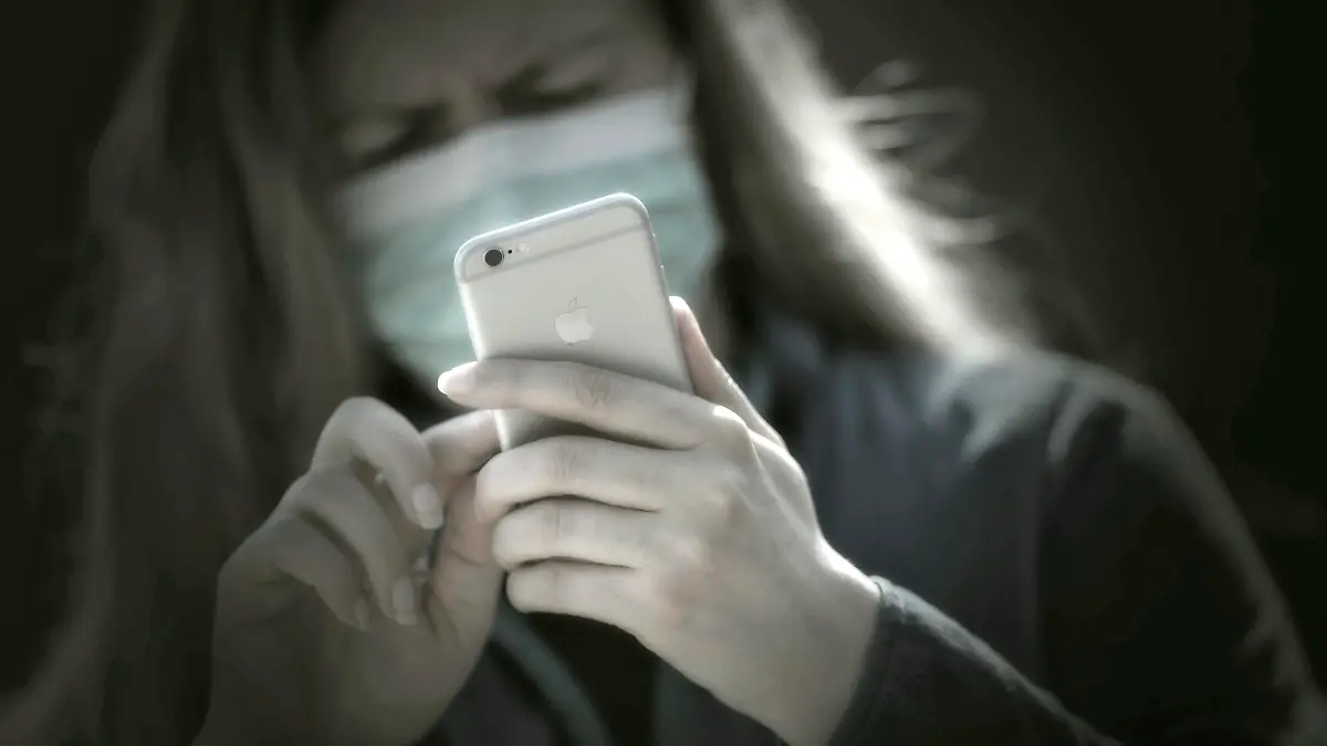 08.04.2020, Symbolbild, Corona-Krise, Frau schaut auf ihr Handy mit Gesichtsmaske. 08.04.2020, Corona-Krise Handy-Nutzung 08.04.2020, Corona-Krise Handy-Nutzung *** 08 04 2020, Symbol picture, Corona crisis, Woman looking at her mobile phone with face mask 08 04 2020, Corona crisis mobile phone use 08 04 2020, Corona crisis mobile phone use