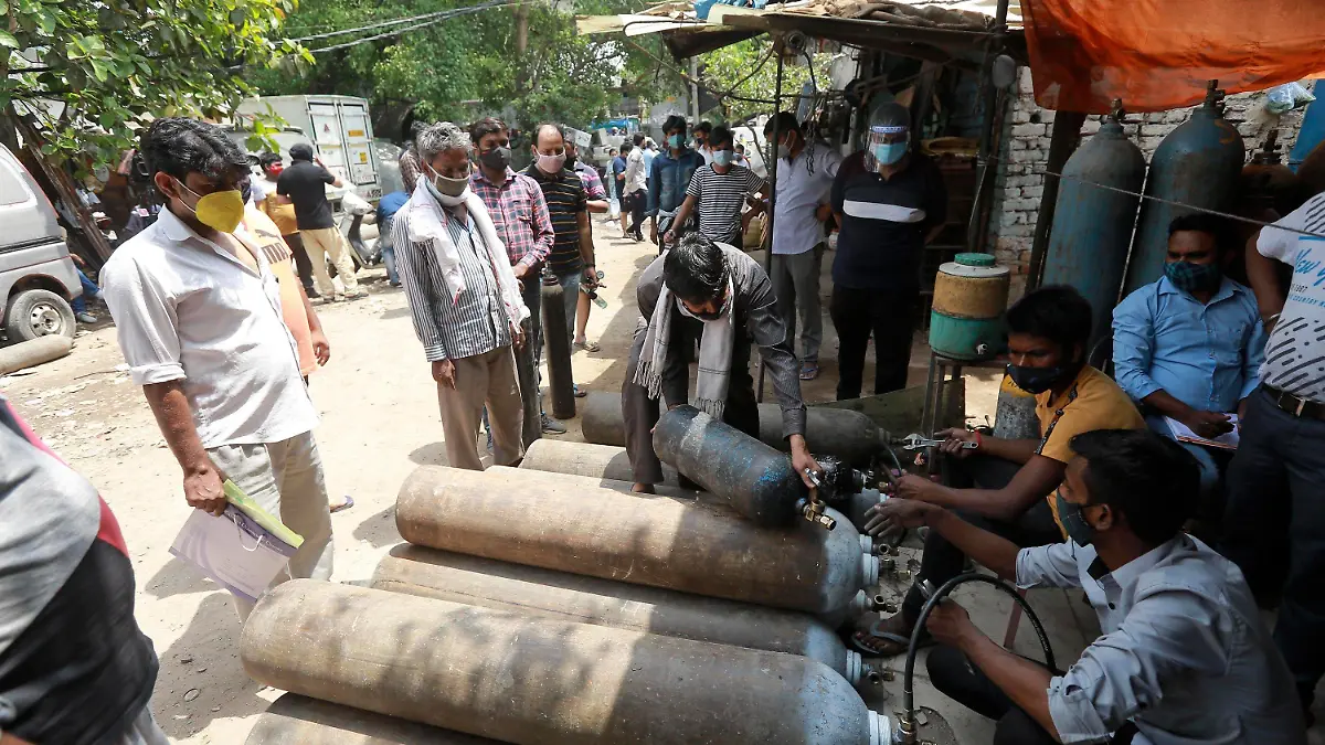 23.04.2021, Indien, Neu-Delhi: Menschen stehen Schlange, um Sauerstoffflaschen aufzufüllen. Indien transportierte Sauerstofftankwagen auf spezielle Schnellzügen in die Stadt, als große Krankenhäuser in Neu-Delhi in den sozialen Medien um mehr Nachschub baten, um Corona-Patienten mit Sauerstoffmangel zu retten. Indiens unterfinanziertes Gesundheitssystem kollabiert angesichts der bislang schlimmsten Corona-Welle, weltweit. Indien verzeichnete mit 332.730 neuen Corona-Infektionen innerhalb eines Tages den zweiten Tag in Folge einen weltweiten Höchstwert auf. Foto: Uncredited/AP/dpa +++ dpa-Bildfunk +++
