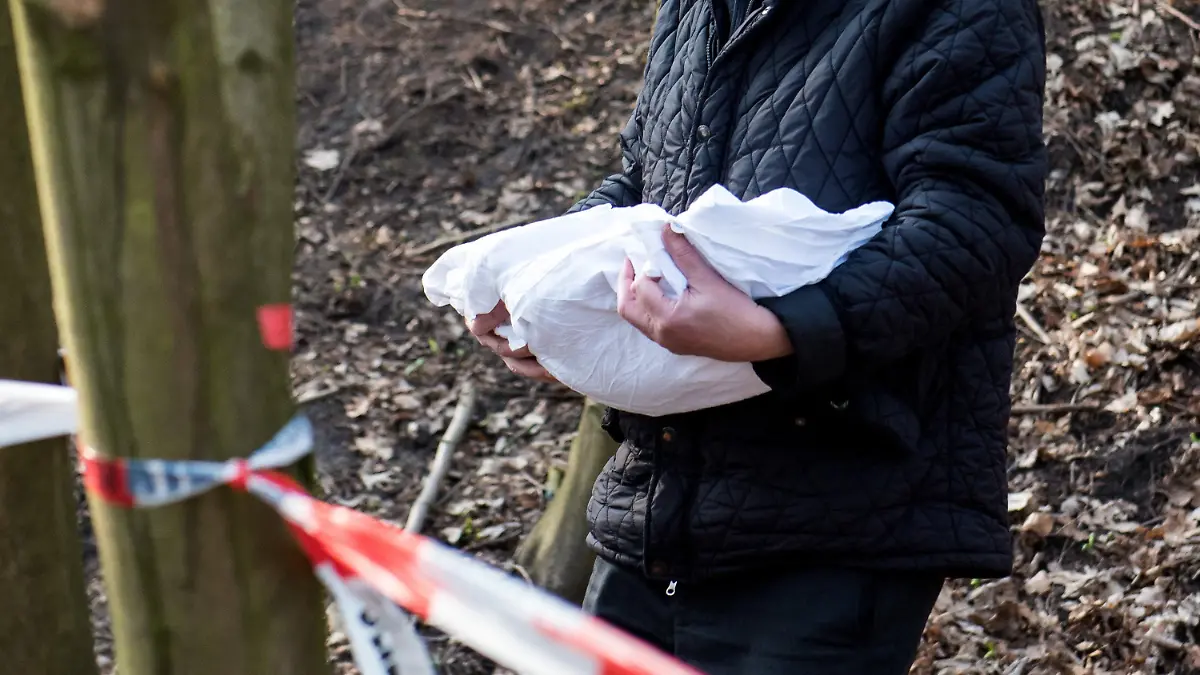 ARCHIV - 22.03.2019, Schleswig-Holstein, Glinde: Ein Bestatter trägt eine Babyleiche, die Schüler am Vormittag entdeckt haben, aus einem Waldstück. In Glinde startet eine DNA-Reihenuntersuchung im Fall des toten Babys. Die Ermittlungen zur Herkunft des Kindes wurden eingestellt. (Zu dpa «Herkunft des toten Babys von Glinde bleibt unbekannt») Foto: Daniel Bockwoldt/dpa +++ dpa-Bildfunk +++