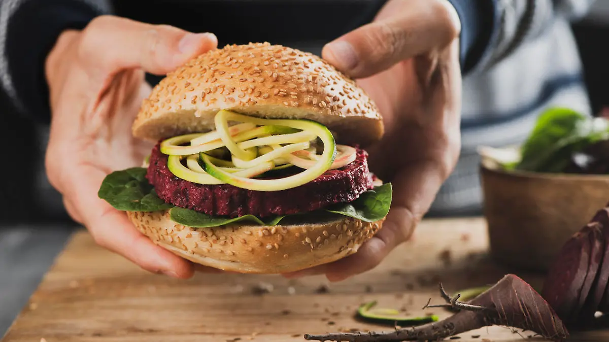 Ein junger Mann hält einen appetitlichen Veggie-Burger in der Hand