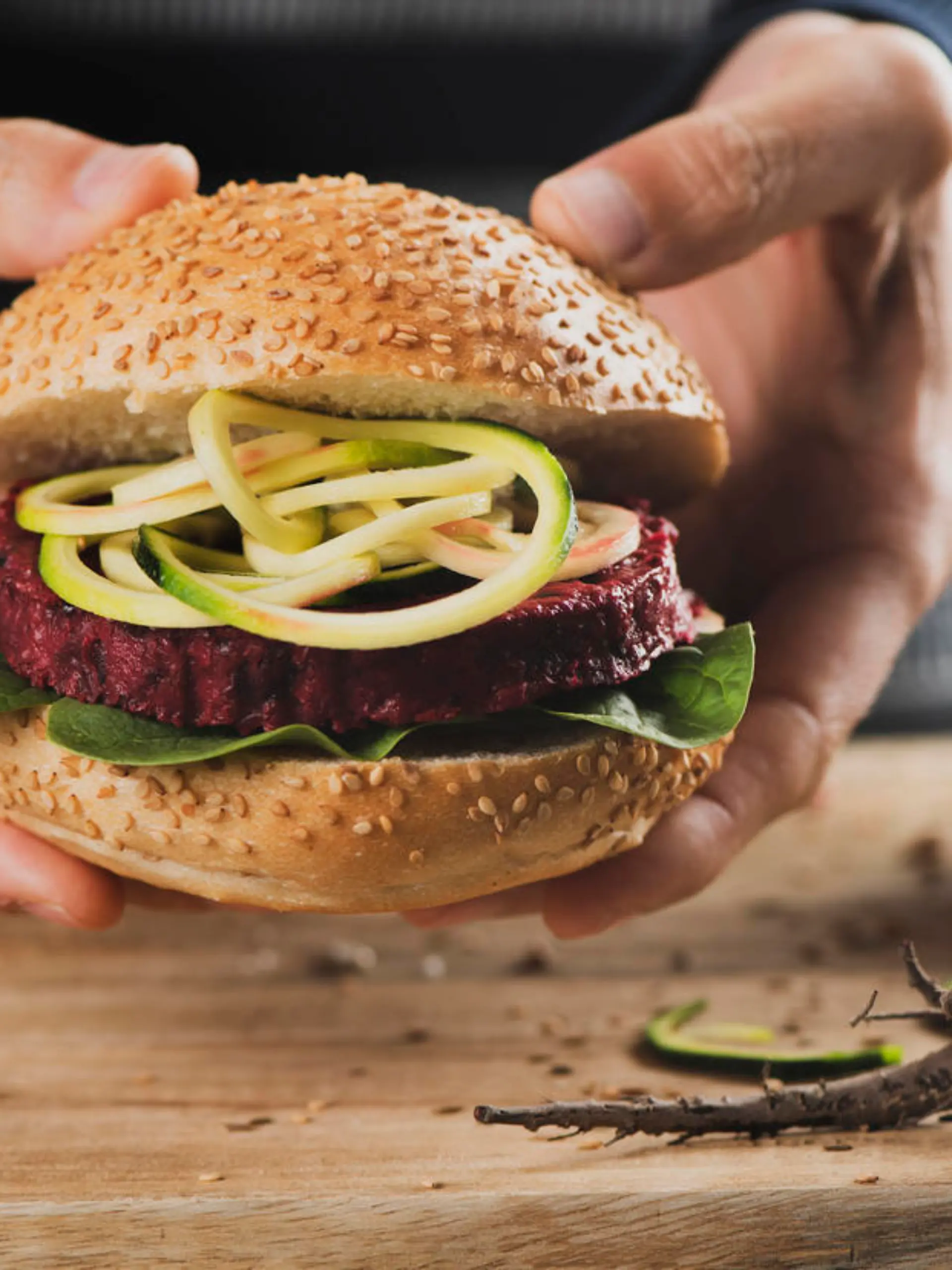 Ein junger Mann hält einen appetitlichen Veggie-Burger in der Hand