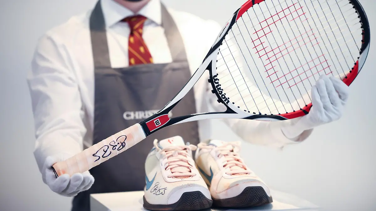 A Christie's gallery assistant poses with the racket and sneakers from the 'French Open, 2009' lot included in 'The Roger Federer Collection', due to be sold at auction, at Christie's auction house in London, Britain, April 27, 2021. Picture taken April 27, 2021. REUTERS/Henry Nicholls