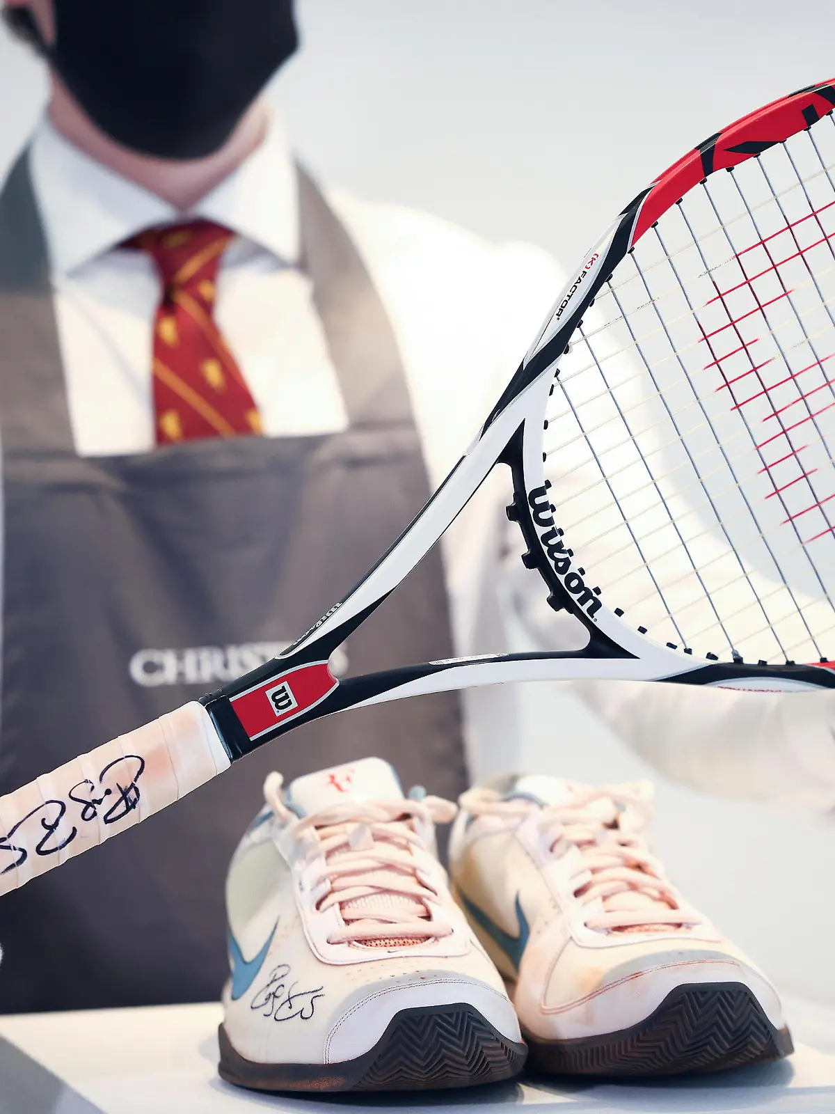 A Christie's gallery assistant poses with the racket and sneakers from the 'French Open, 2009' lot included in 'The Roger Federer Collection', due to be sold at auction, at Christie's auction house in London, Britain, April 27, 2021. Picture taken April 27, 2021. REUTERS/Henry Nicholls