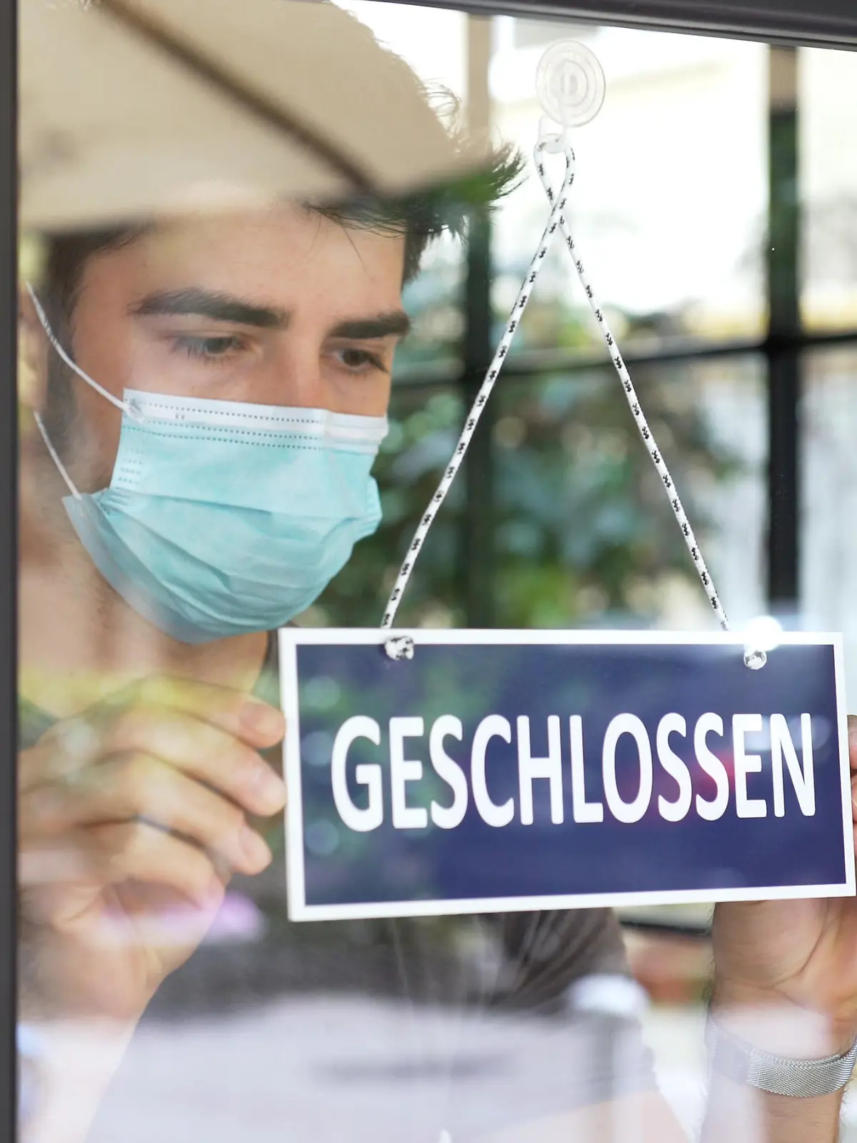 Mann hängt Schild "geschlossen" an die Tür eine Geschäfts