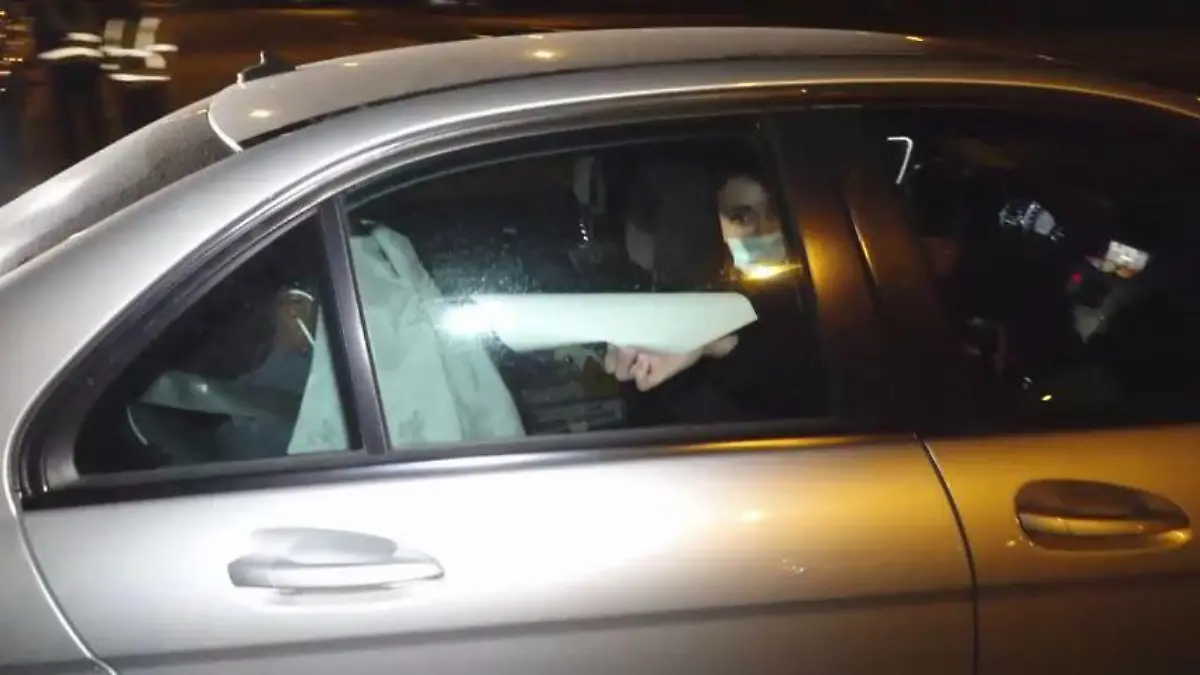 Versteckt hinter einer Jacke. Hier wird die Verdächtige von der Polizei weggefahren.