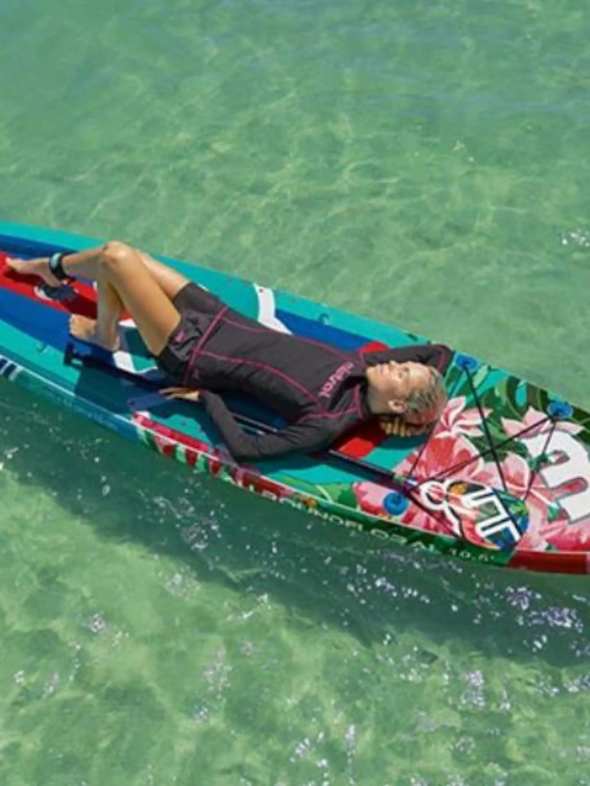 Frau liegt auf einem Stand Up Paddling Board im Wasser.