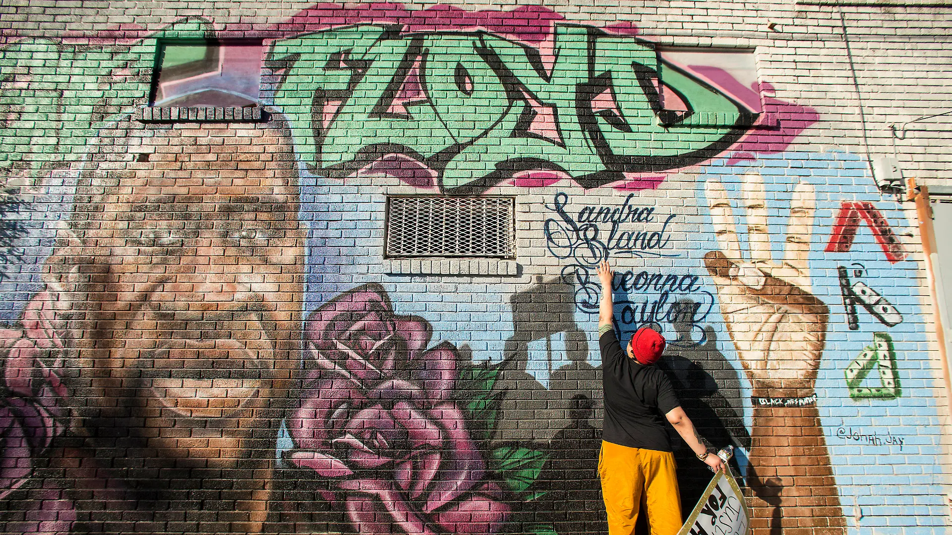 Daryel Simmons reaches up to touch the names of Sandra Bland and Breonna Taylor as she came to a George Floyd memorial mural after learning of the guilty verdict on all counts in the murder trial of former Minneapolis Officer Derek Chauvin in the death of George Floyd on Tuesday, April 20, 2021, in Houston.  (Brett Coomer/Houston Chronicle via AP)