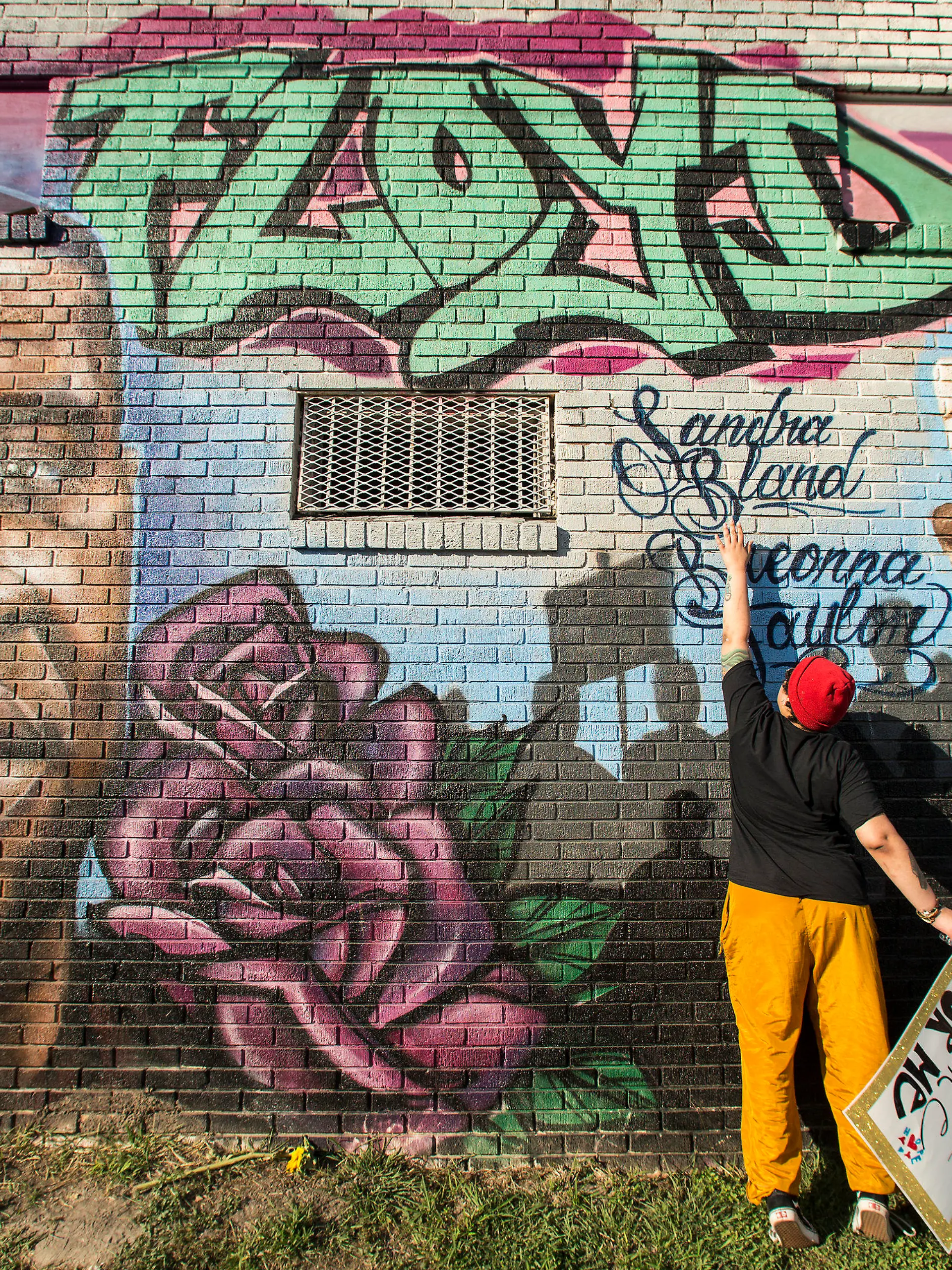 Daryel Simmons reaches up to touch the names of Sandra Bland and Breonna Taylor as she came to a George Floyd memorial mural after learning of the guilty verdict on all counts in the murder trial of former Minneapolis Officer Derek Chauvin in the death of George Floyd on Tuesday, April 20, 2021, in Houston.  (Brett Coomer/Houston Chronicle via AP)