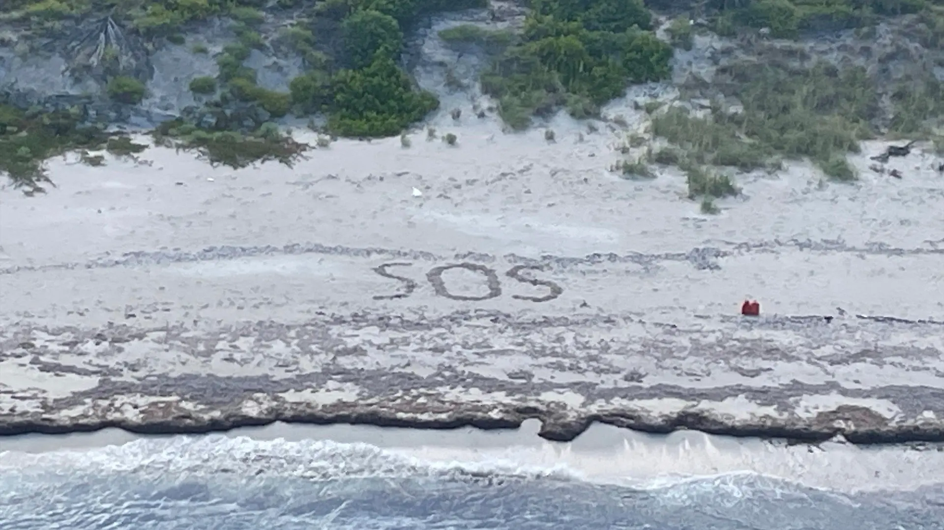 HANDOUT - 18.08.2023, Bahamas, Cay Sal: Dieses von der US-Küstenwache zur Verfügung gestellte Foto zeigt die Buchstaben «SOS», die wvon einem 64-jährigen Mann in den Sand gezeichnet wurden, der drei Tage lang auf einer Insel in den Bahamas gestrandet war, bis er gerettet wurde. Die US-Küstenwache hat ein Foto mit einem «SOS»-Schriftzug veröffentlicht, der bei der Rettung eines gestrandeten Mannes von einer Bahamas-Insel geholfen hat. Der 64-Jährige habe drei Tage auf der Insel Cay Sal ausgeharrt und sei am Freitag gerettet worden, teilte die Küstenwache mit. Foto: Uncredited/U.S. Coast Guard/AP/dpa - ACHTUNG: Nur zur redaktionellen Verwendung und nur mit vollständiger Nennung des vorstehenden Credits +++ dpa-Bildfunk +++