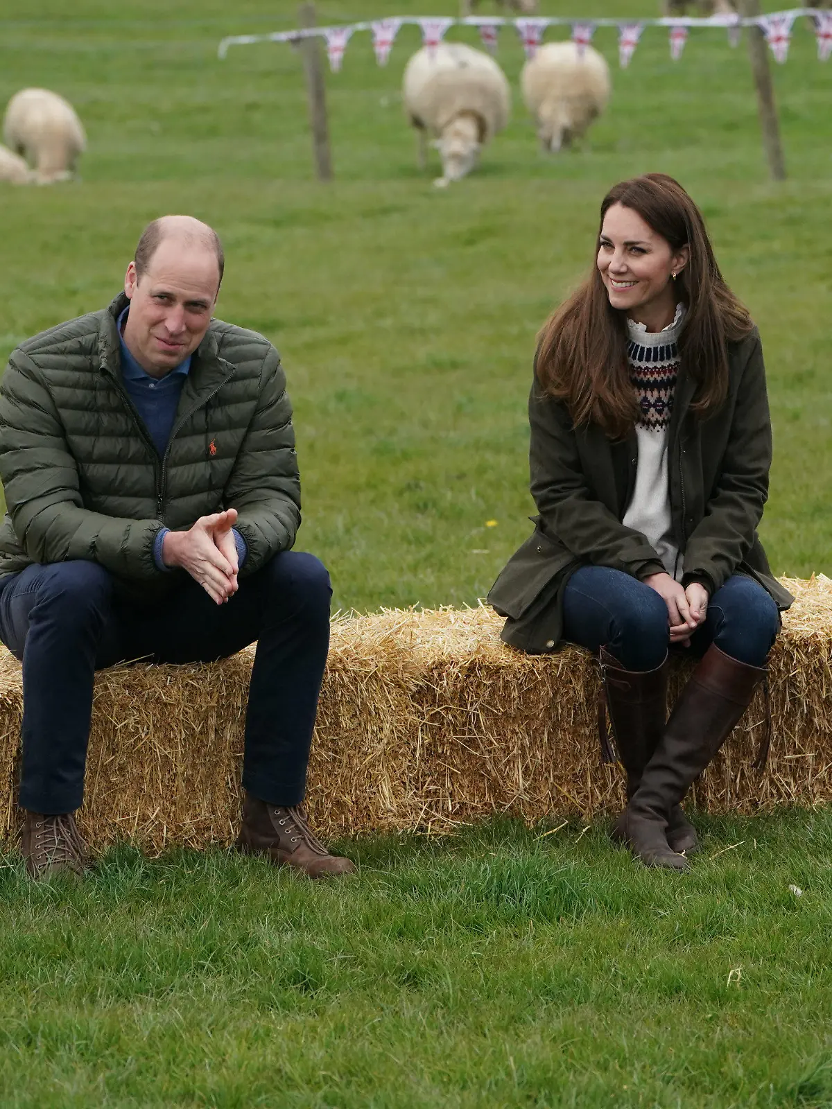 27.04.2021, Großbritannien, Darlington: Prinz William (l), Herzog von Cambridge, und Prinz Kate, Herzogin von Cambridge, sitzen bei ihrem Besuch auf der Manor Farm auf Strohballen. Foto: Owen Humphreys/PA Wire/dpa +++ dpa-Bildfunk +++