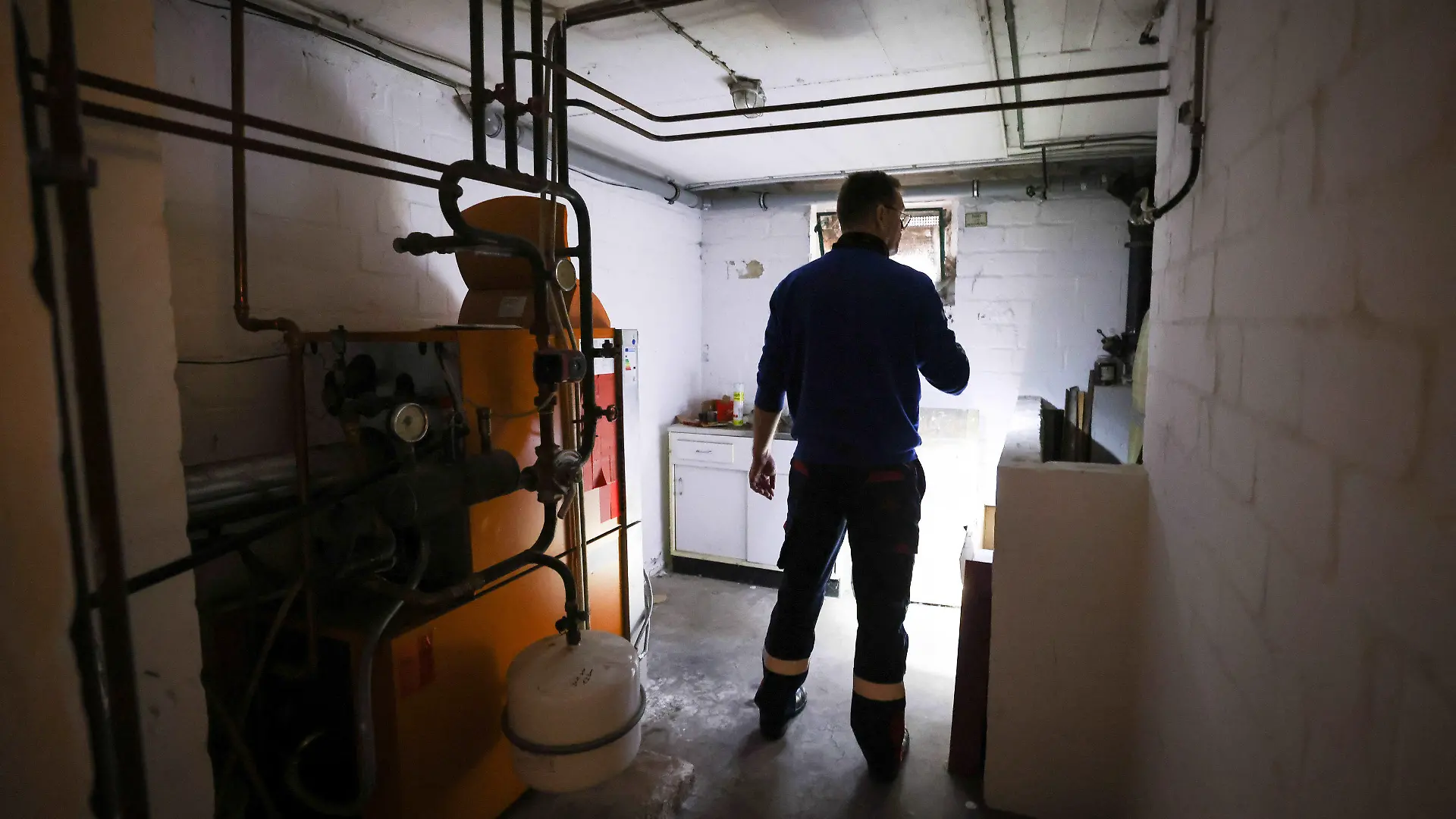 ARCHIV - 09.11.2021, Schleswig-Holstein, Itzehoe: Ein Mitarbeiter eines Diesel- und Heizöl-Unternehmens prüft die Kunststofftanks in einem Heizungskeller bei der Heizöllieferung für ein Einfamilienhaus.      (zu dpa "Ministerien arbeiten an Entwurf zum Verbot neuer Ölheizungen") Foto: Christian Charisius/dpa +++ dpa-Bildfunk +++