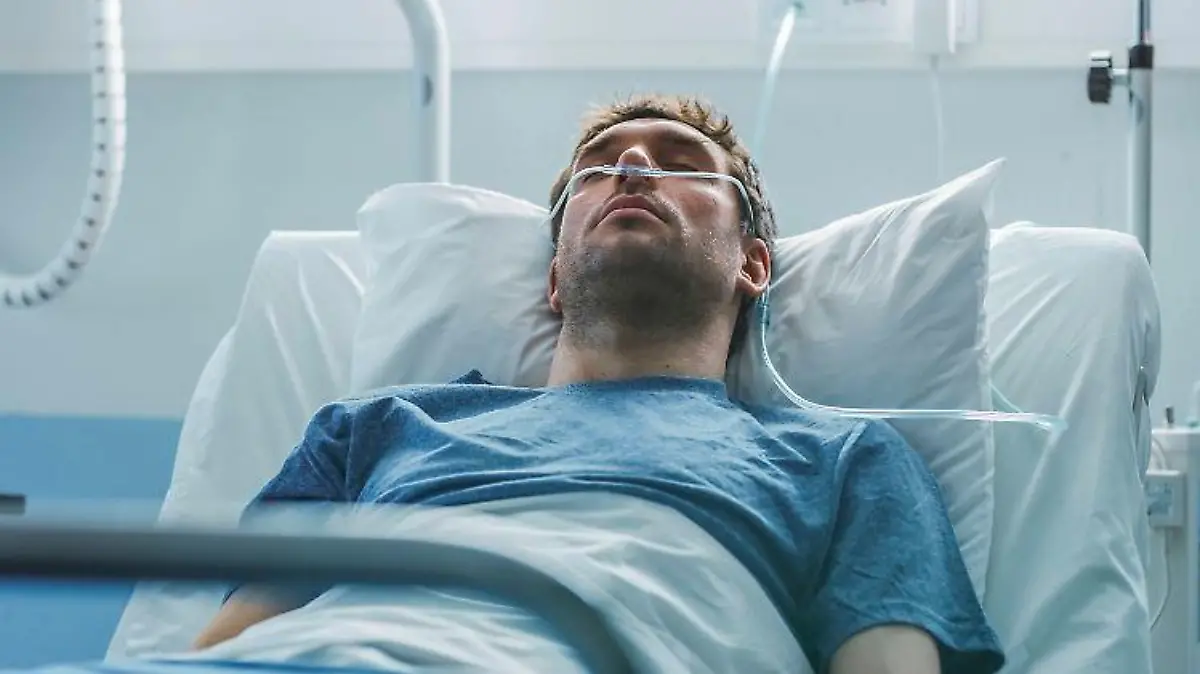 Ein junger Patient wird in einem Krankenhausbett durch die Nase beatmet.