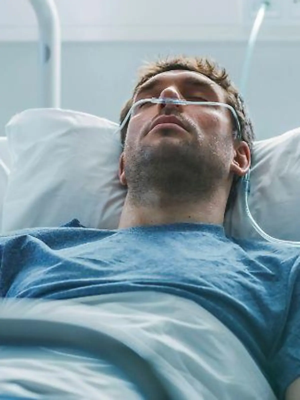 Ein junger Patient wird in einem Krankenhausbett durch die Nase beatmet.