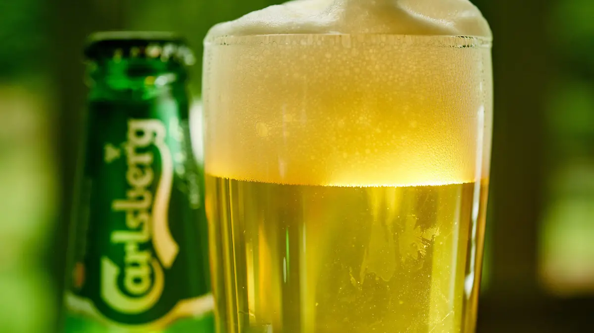 ARCHIV - 12.06.2018, Nordrhein-Westfalen, Herdecke: ILLUSTRATION - Ein Glas Bier und eine Bierflasche der Marke Carlsberg stehen auf einem Tisch. Wegen ihrer Beteiligung am Bierkartell ist die Brauerei Carlsberg vom Oberlandesgericht Düsseldorf zu einer Geldbuße in Höhe von 50 Millionen Euro verurteilt worden. (zu dpa «Bierkartell: 50-Millionen-Euro-Geldbuße für Carlsberg») Foto: Bernd Thissen/dpa +++ dpa-Bildfunk +++