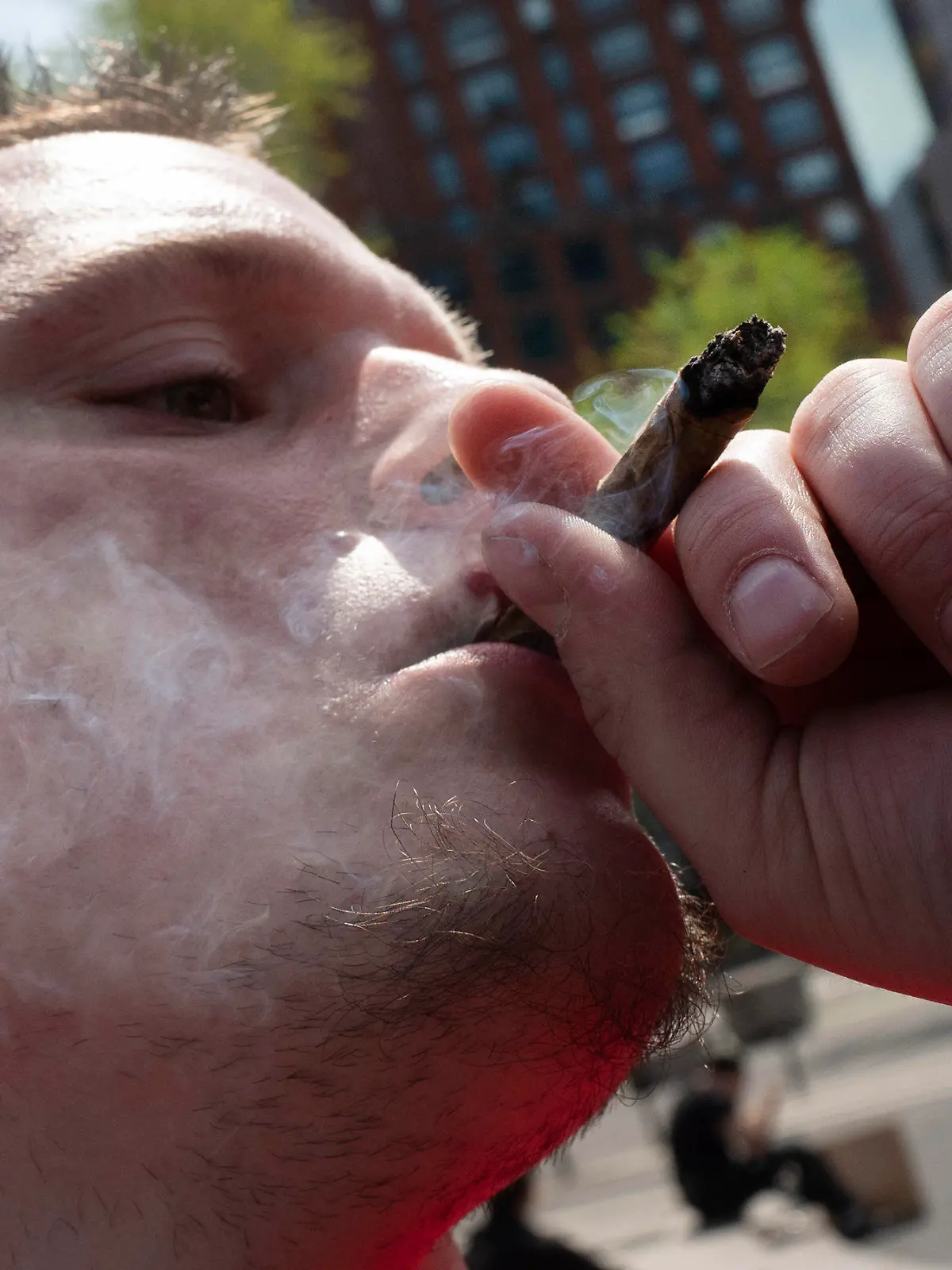 20.04.2021, USA, New York: Michael Keren raucht bei der «Joints for Jabs»-Veranstaltung (etwa "Joints für eine Injektion") einen Joint. Personen, die einen Corona-Impfnachweis vorzeigten, erhielten einen kostenlosen Joint. Der Konsum von Marihuana ist im Bundesstaat New York zuvor legalisiert worden. Foto: Mark Lennihan/AP/dpa +++ dpa-Bildfunk +++