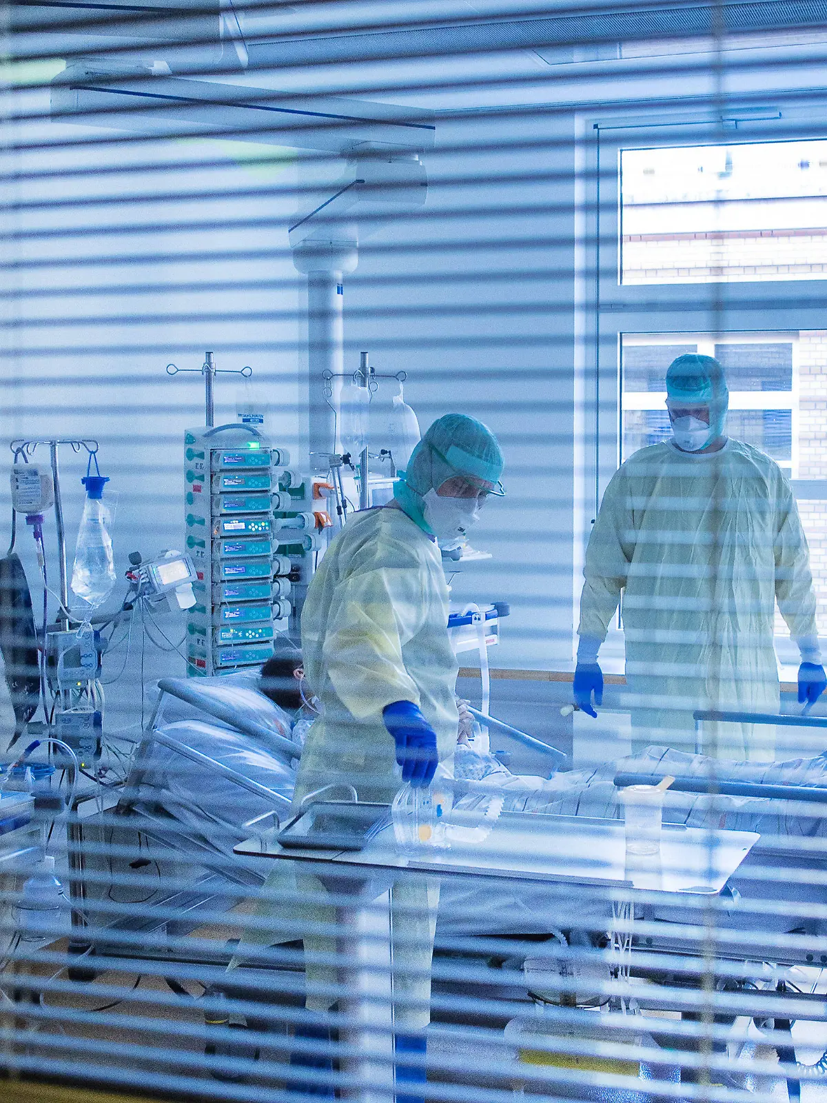 ARCHIV - 23.11.2020, Mecklenburg-Vorpommern, Greifswald: Mediziner und Pfleger versorgen einen an Covid-19 erkrankten Patienten in einem Zimmer des besonders geschützten Teils der Intensivstation des Universitätsklinikums Greifswald. (zu dpa "Engpass bei Intensivbetten droht - Verlegung von Patienten") Foto: Jens Büttner/dpa-Zentralbild/dpa +++ dpa-Bildfunk +++