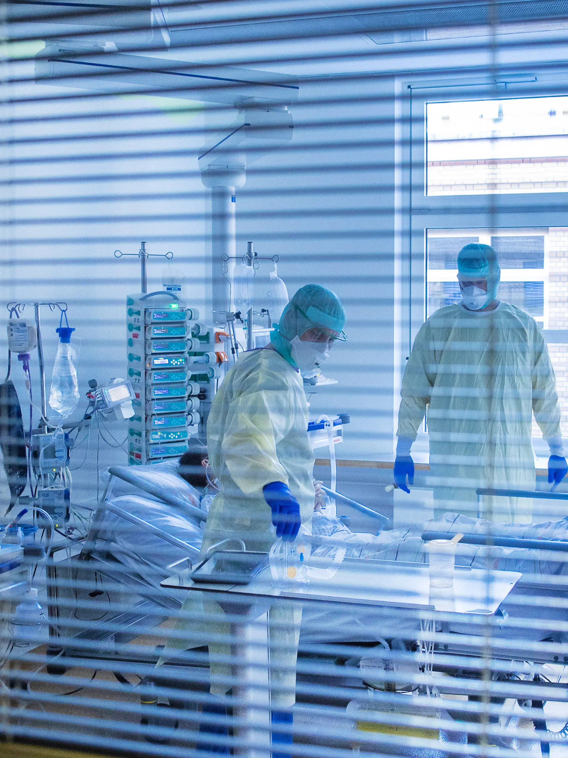ARCHIV - 23.11.2020, Mecklenburg-Vorpommern, Greifswald: Mediziner und Pfleger versorgen einen an Covid-19 erkrankten Patienten in einem Zimmer des besonders geschützten Teils der Intensivstation des Universitätsklinikums Greifswald. (zu dpa "Engpass bei Intensivbetten droht - Verlegung von Patienten") Foto: Jens Büttner/dpa-Zentralbild/dpa +++ dpa-Bildfunk +++