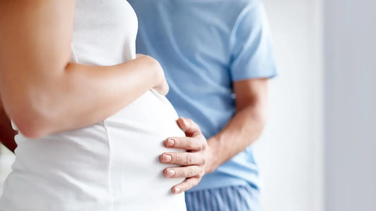 Mann hält Hand auf Schwangerschaftsbauch