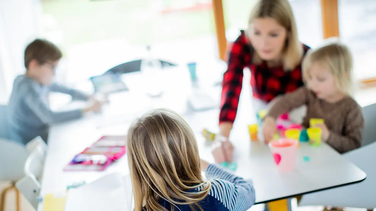 dpatopbilder - 14.01.2021, Nordrhein-Westfalen, Haltern am See: Eine Lehrerin sitzt mit ihren drei Kindern im Wohnzimmer, unterrichtet ihre Schüler einer Berufsschule im Distanzunterricht und hilft ihren Kindern bei ihren Aufgaben für die Schule. Um die Ausbreitung des Coronavirus zu verlangsamen, sind die Schulen geschlossen. Alle Schüler müssen im Lockdown zu Hause lernen. Foto: Rolf Vennenbernd/dpa +++ dpa-Bildfunk +++