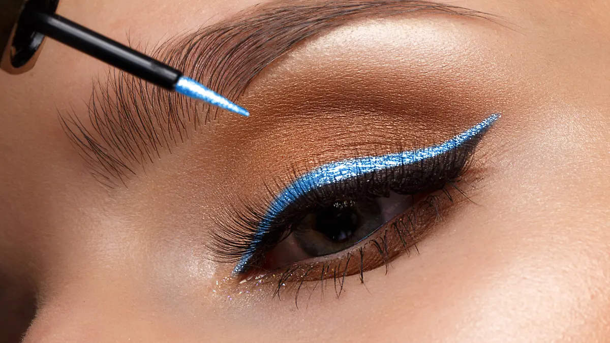 Frau, die blauen Eyeliner aufträgt.