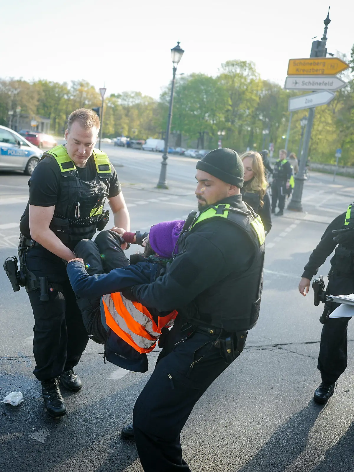 28.04.2023, Berlin: Polizeibeamte tragen eine Klimaaktivistin von der Straße am Großen Stern vor der Siegessäule. Hier haben sich zuvor Aktivisten der Klimabewegung Letzte Generation auf die Fahrbahn gesetzt und die Hand auf den Asphalt geklebt. Foto: Kay Nietfeld/dpa +++ dpa-Bildfunk +++