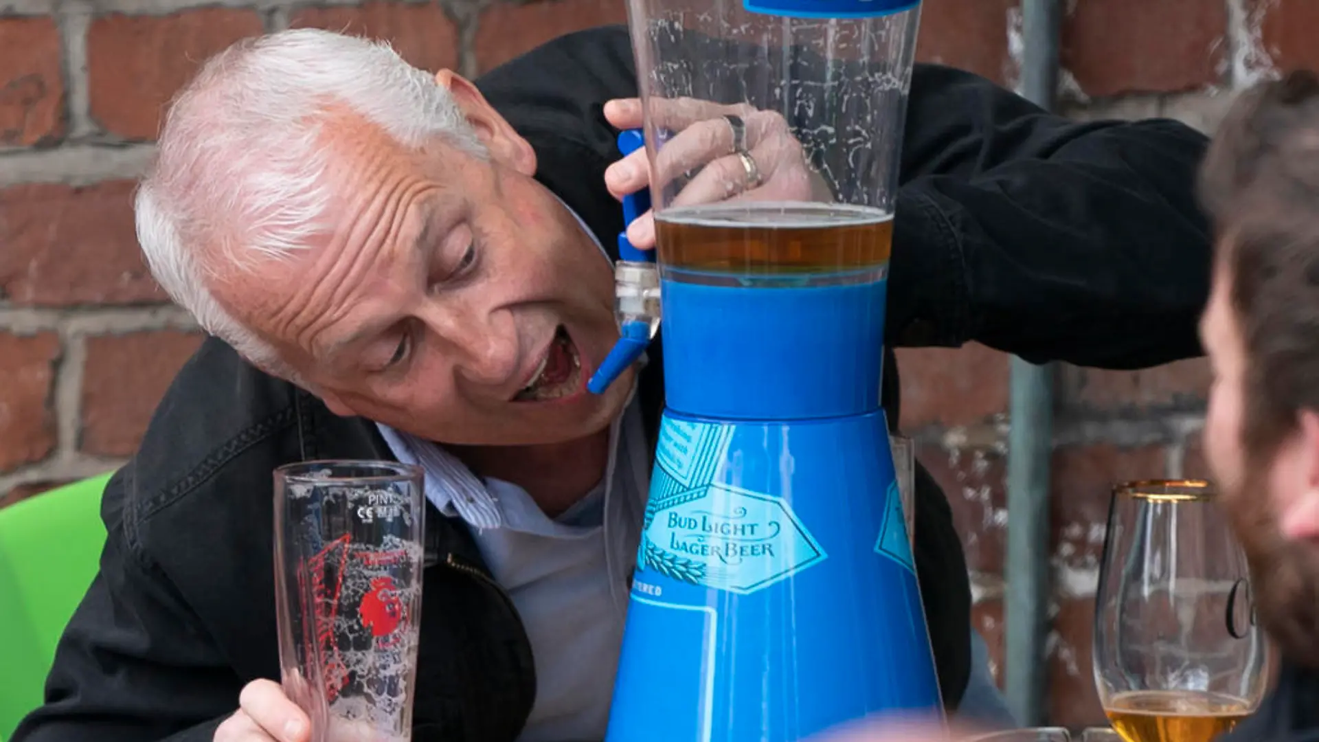 A member of the public pretends to take a swig from a beer tap outside a bar in Manchester Monday, April 12, 2021, as restaurants, bars and pubs can open and serve people who can be seated outside. Millions of people in England will get their first chance in months for haircuts, casual shopping and restaurant meals on Monday, as the government takes the next step on its coronavirus lockdown-lifting road map. (AP Photo Jon Super)