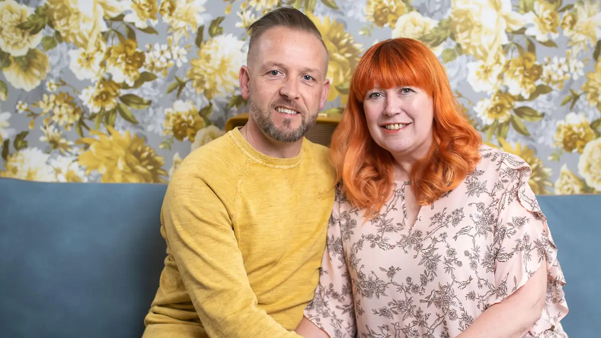 Claire und David sitzen auf ihrer gemeinsamen Couch.