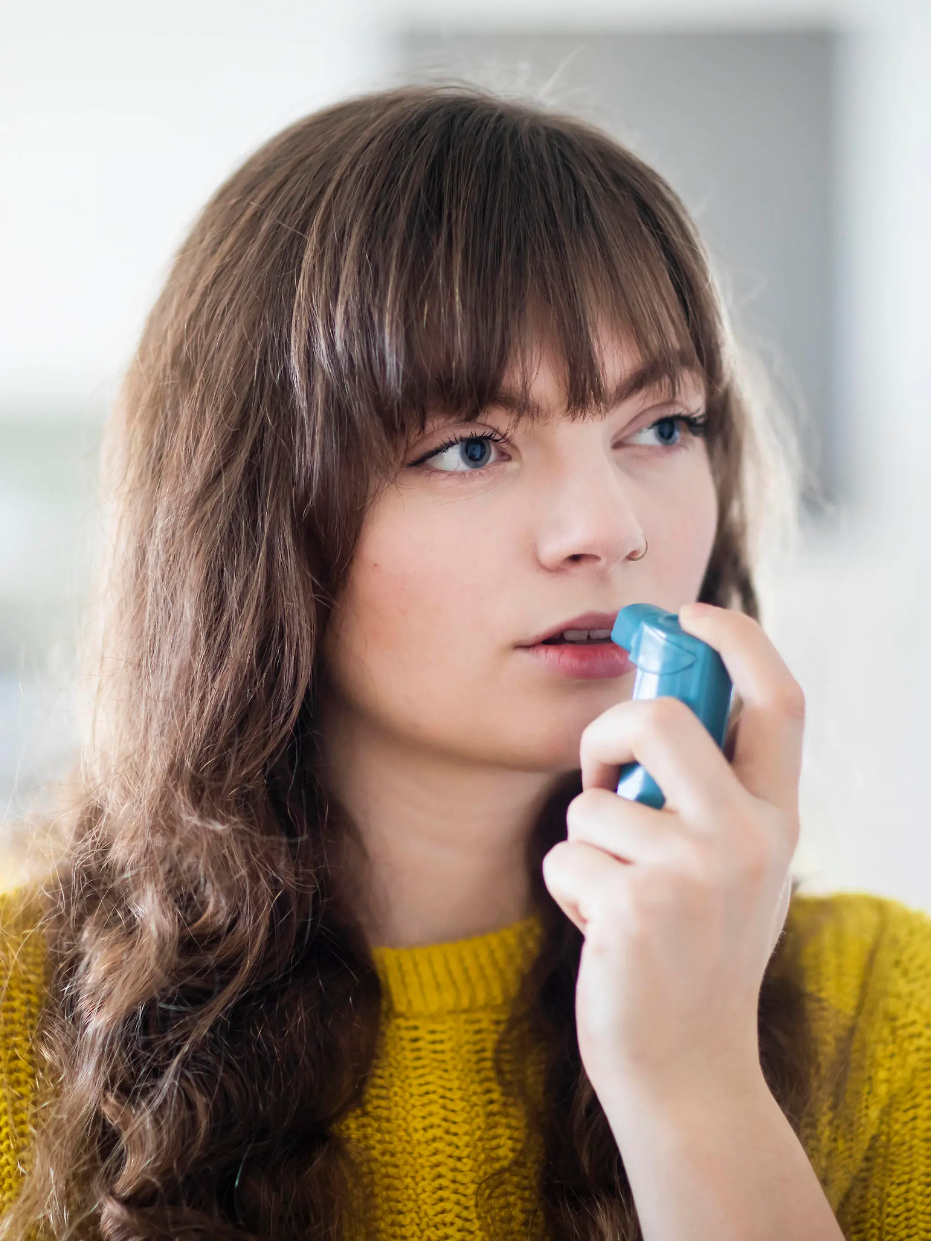  Female breathing through asthma inhaler while looking away model released Symbolfoto property released SGF02750