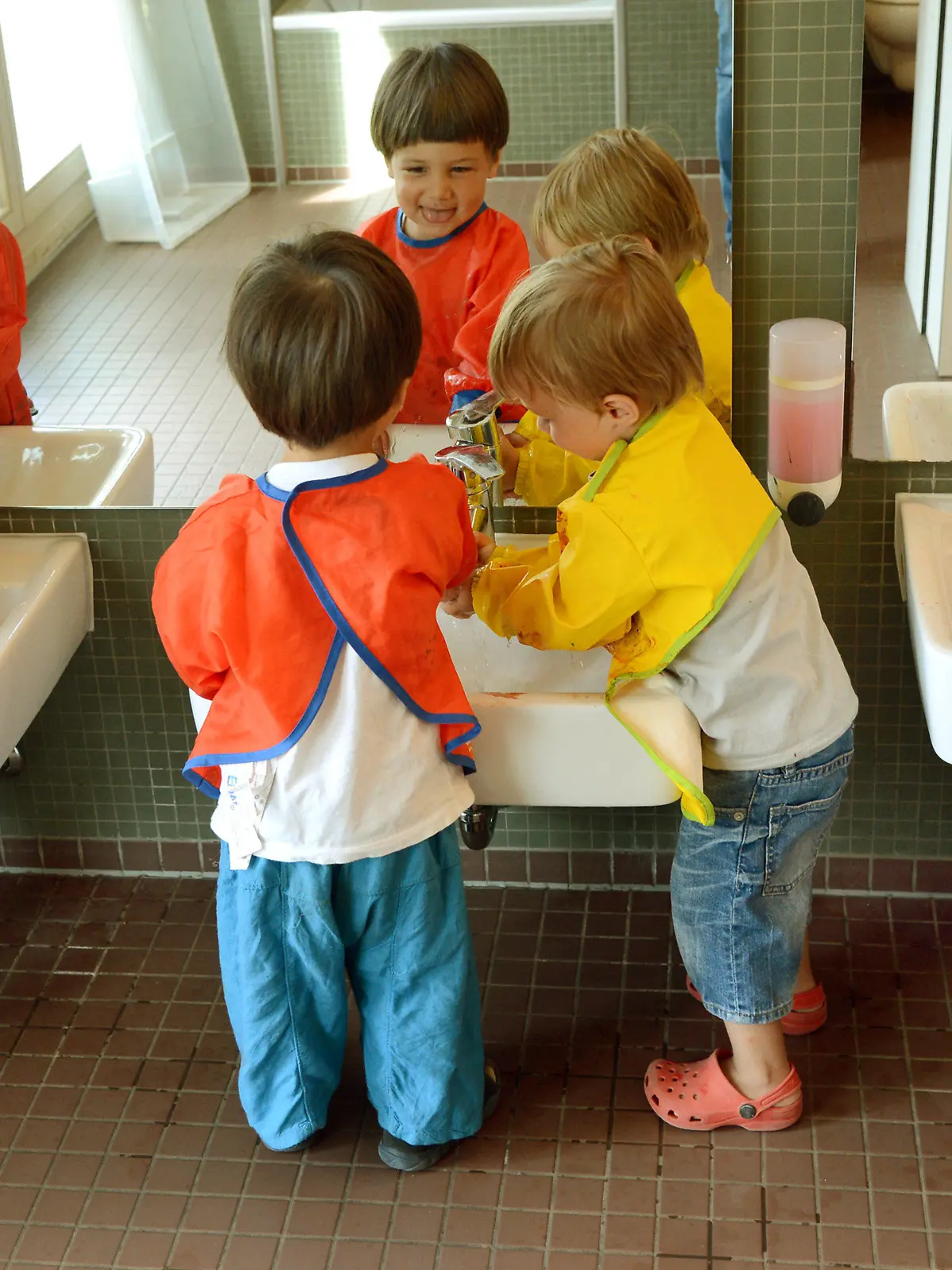 ARCHIV - Nach dem Malen mit Wasserfarben waschen sich die mit bunten Schürzen ausgestatteten Krippenkinder (1,5 bis 3 Jahre) am 24.07.2013 in der BBW-Kindertageseinrichtung «forum thomanum» in Leipzig. Foto: Waltraud Grubitzsch/dpa (zu lsn «Kommunen wollen vom Land mehr Geld für Kitas» vom 13.08.2013) +++(c) dpa - Bildfunk+++