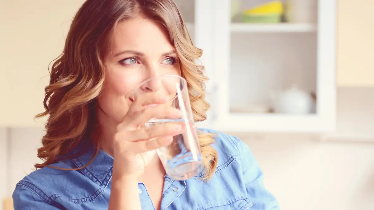 Frau trinkt Wasser in Küche