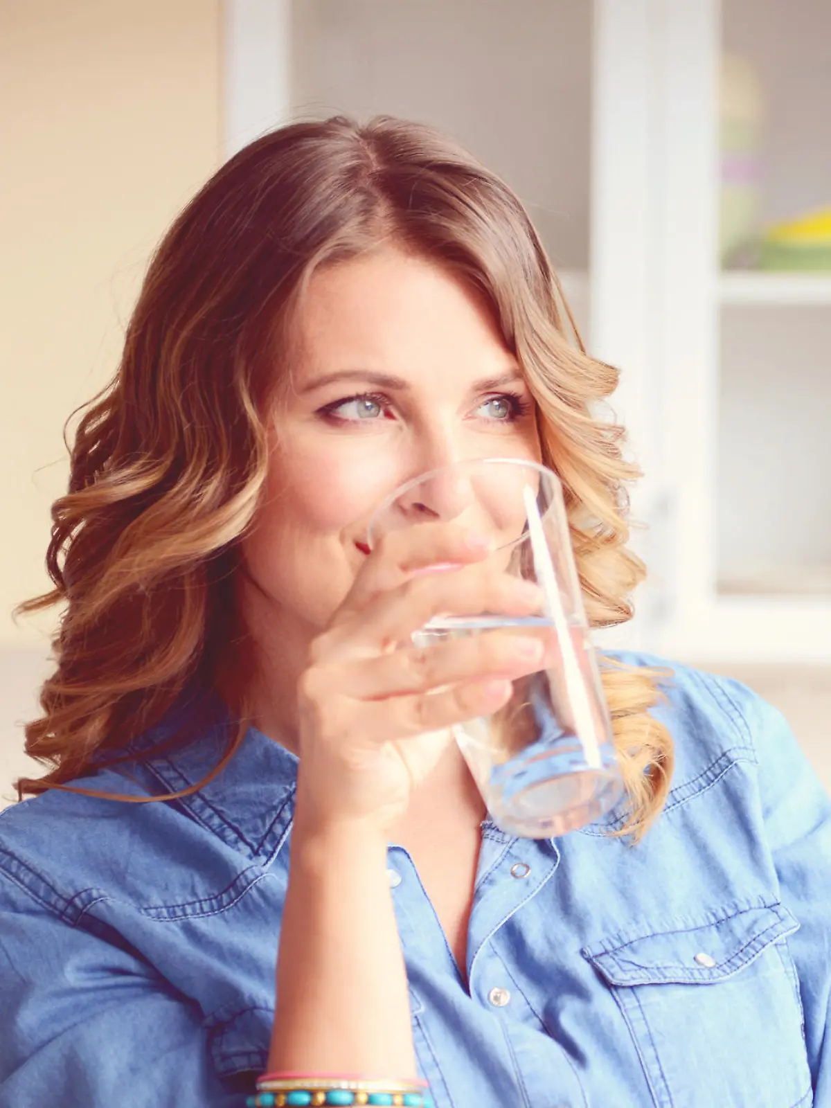 Frau trinkt Wasser in Küche